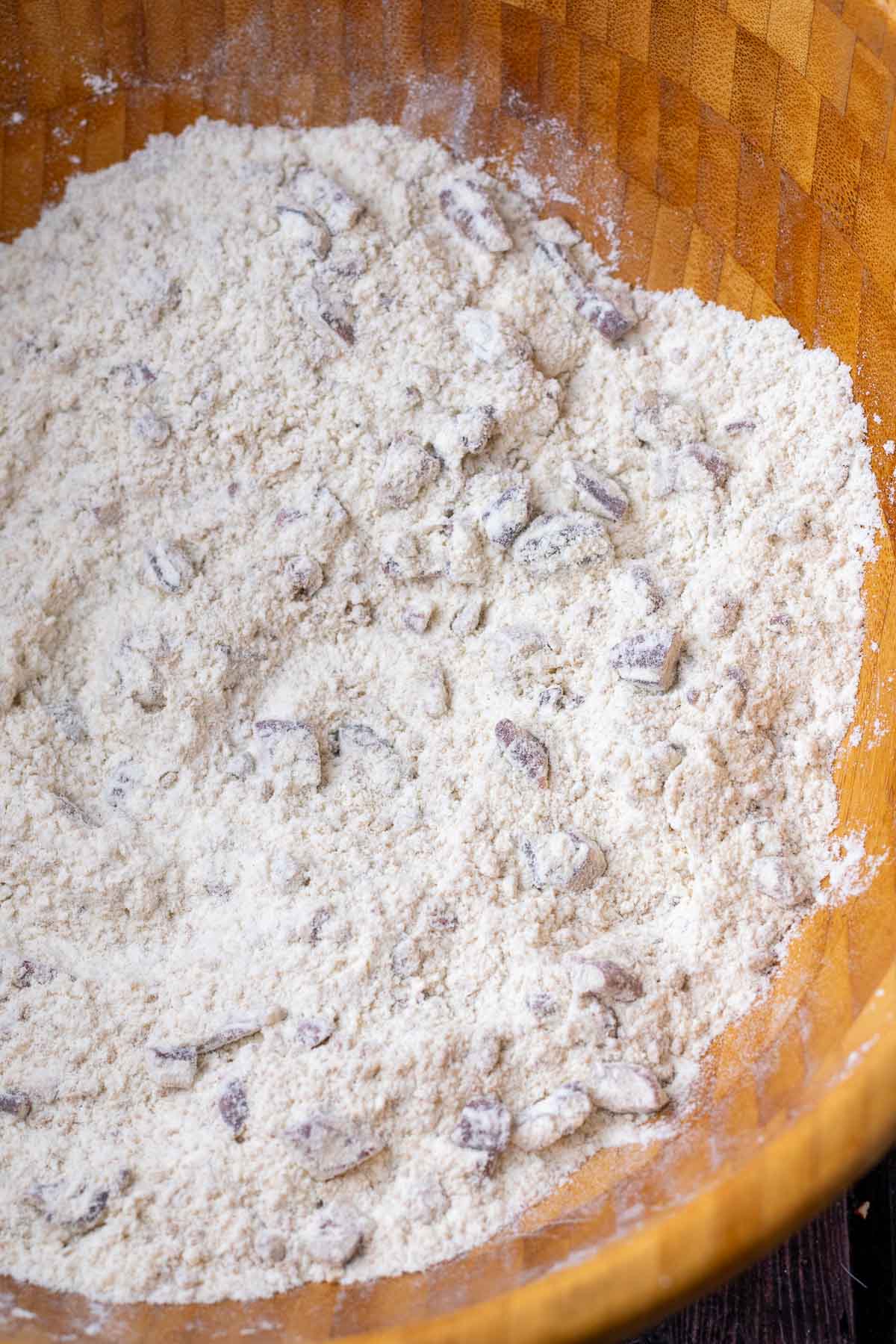 Mixed dry ingredients for sourdough maple pecan scones in a large wooden bowl.