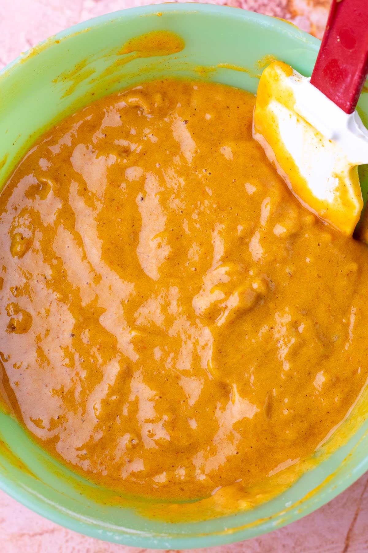 Mixed sourdough pumpkin roll batter in a bowl with a spatula.
