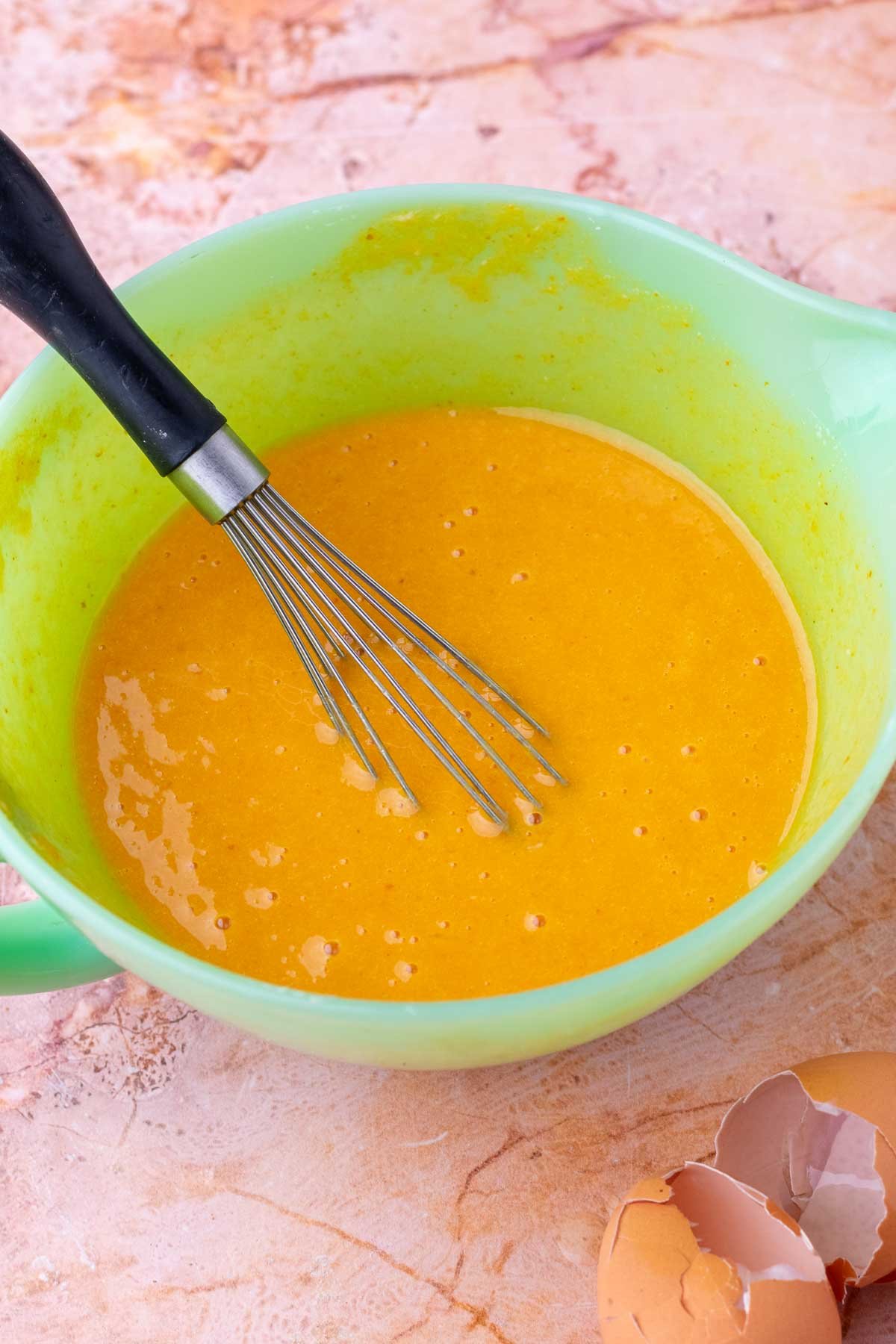 Wet ingredients for sourdough pumpkin roll mixed in a bowl with a whisk.