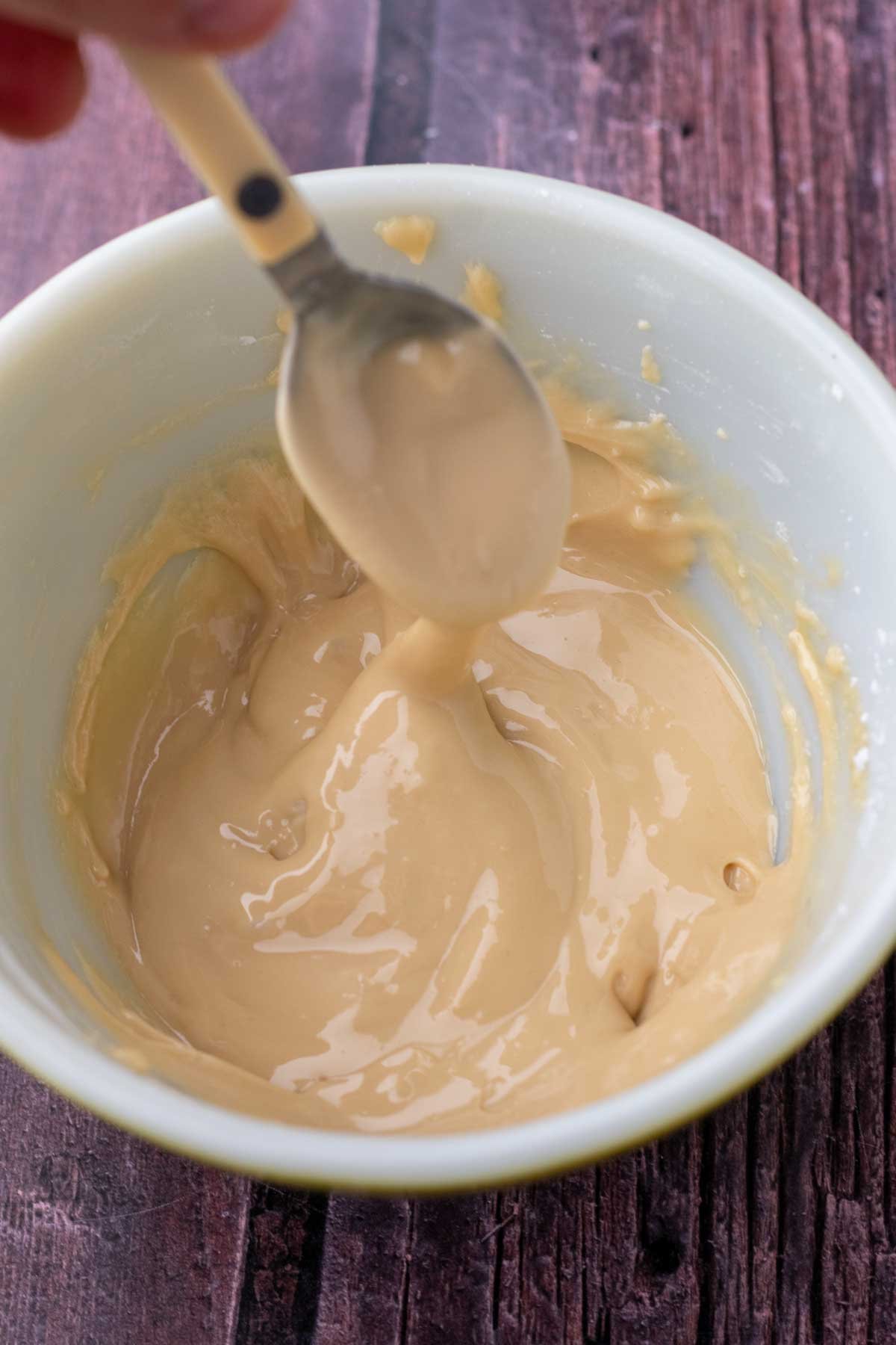 Spoon mixing salted maple glaze in a bowl.