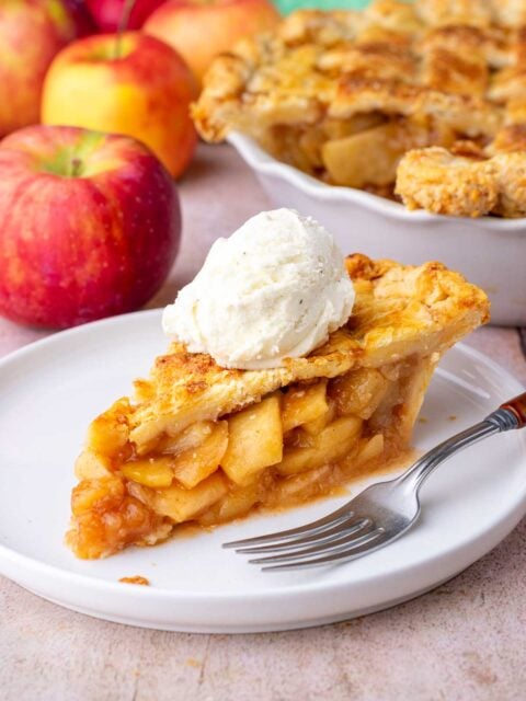 Perfect slice of sourdough apple pie with a scoop of ice cream on a plate with a fork.