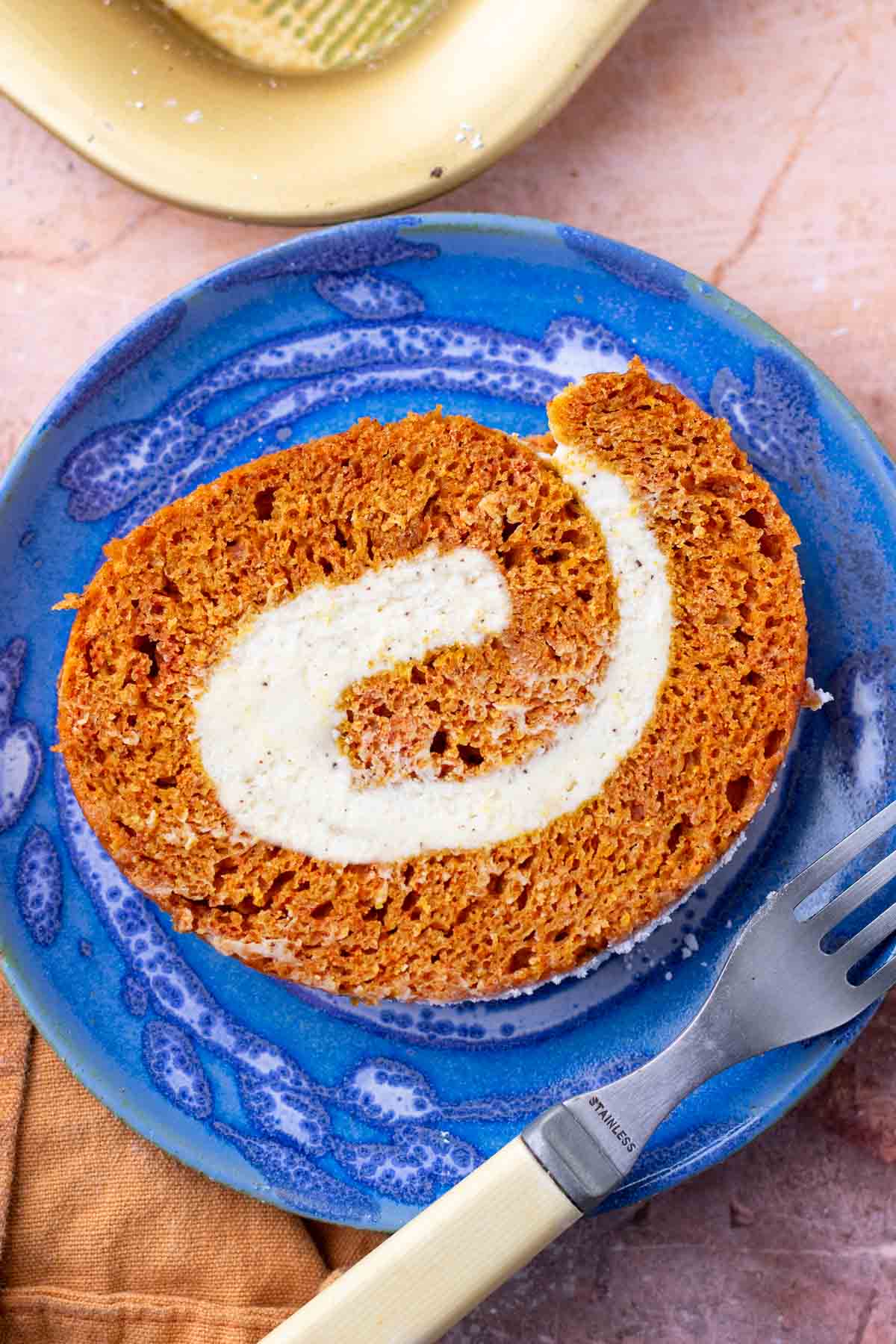 Slice of sourdough pumpkin roll with brown butter cream cheese on a plate with a fork.