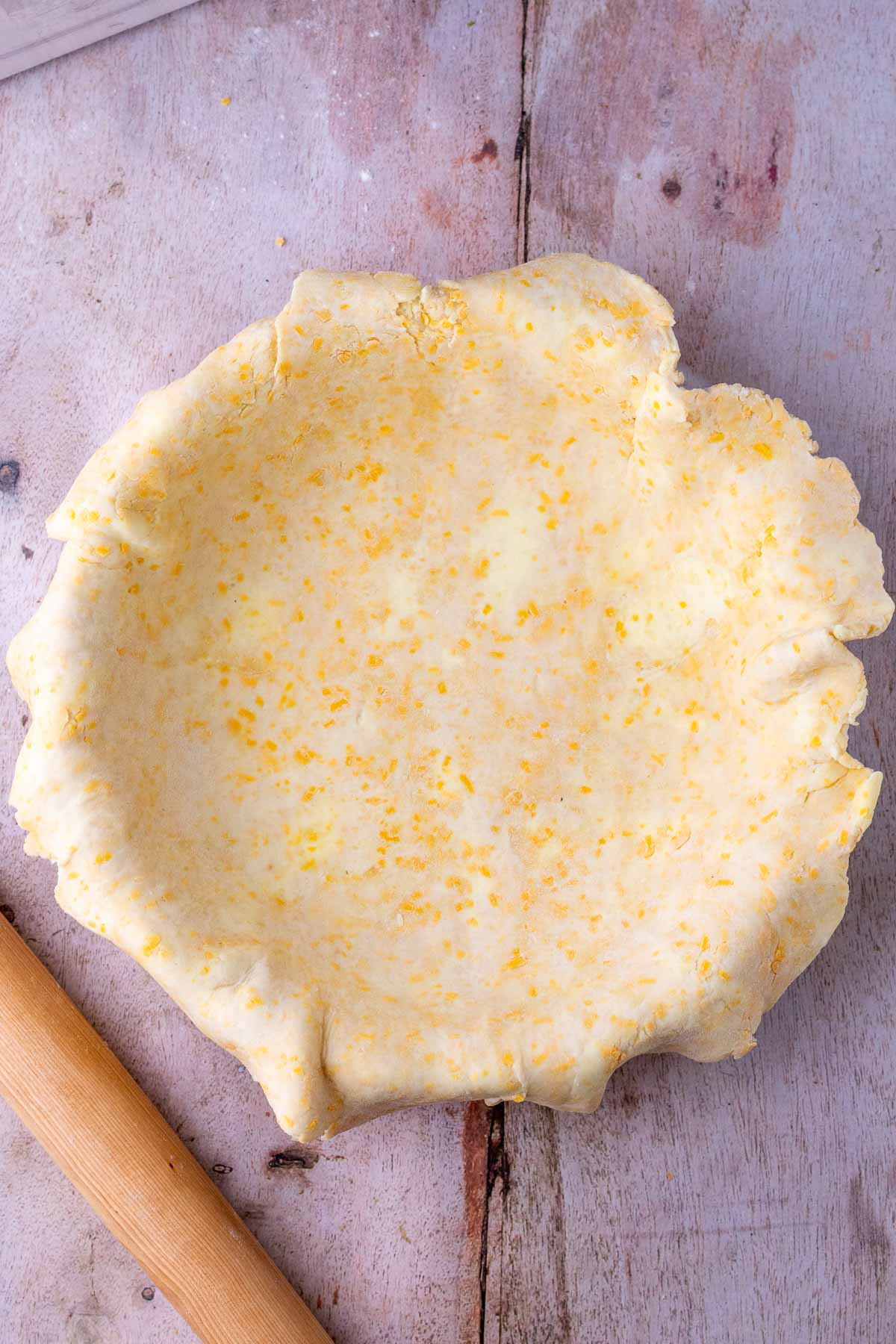 Sourdough cheddar pie crust in pie plate and a rolling pin.