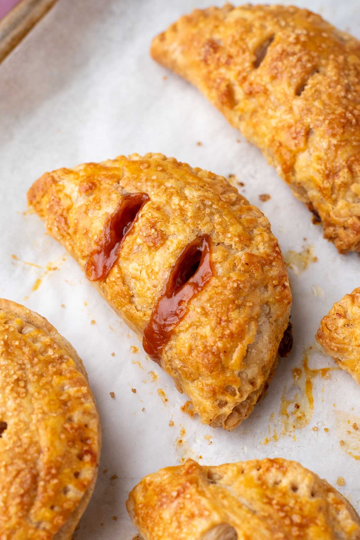 Baked sourdough apple hand pies on a sheet pan with parchment paper.