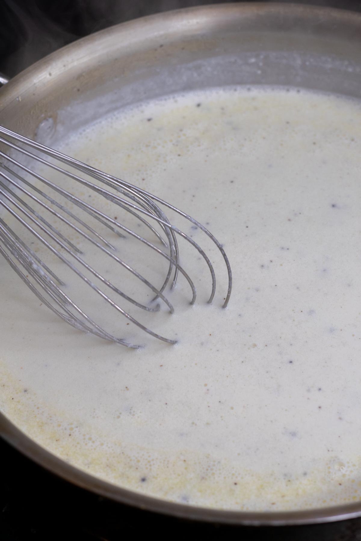 Whisking milk into bechamel sauce for sourdough mac and cheese.