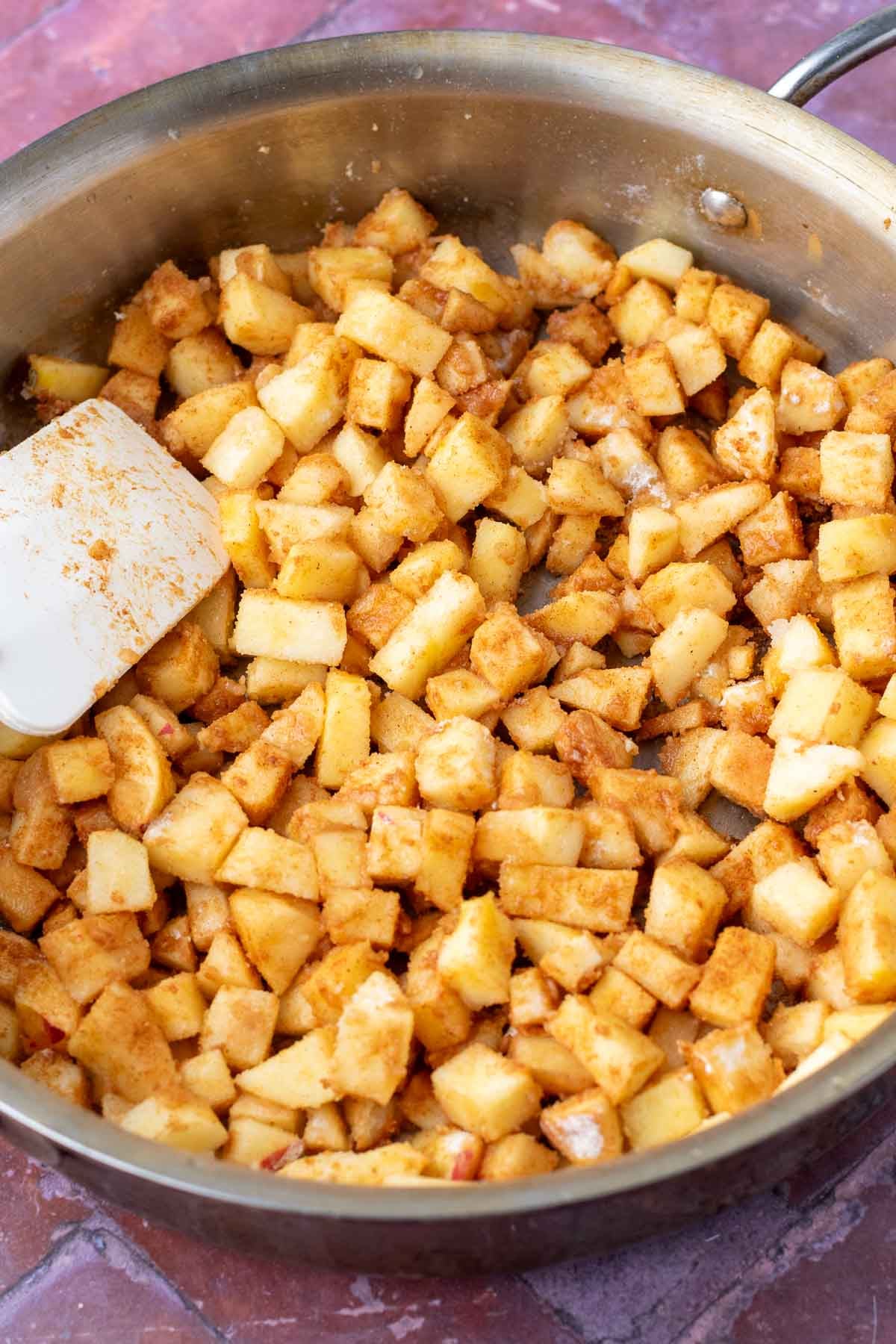 Cooking sourdough apple hand pie filling in a skillet with a spatula.