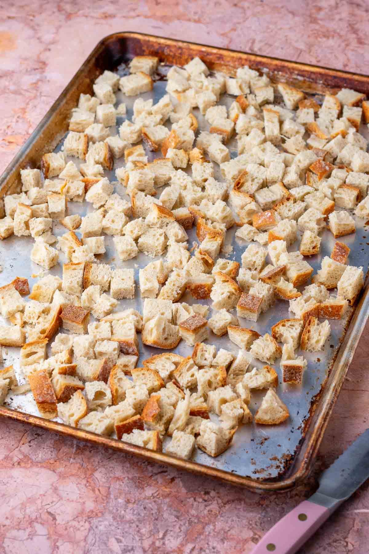 Cubes of sourdough bread on a baking sheet.
