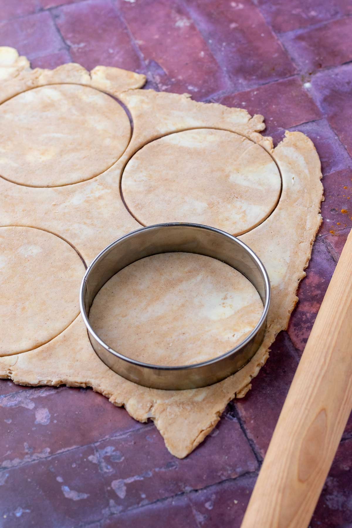 Cutting out sourdough hand pies with a metal cookie cutter and a rolling pin.