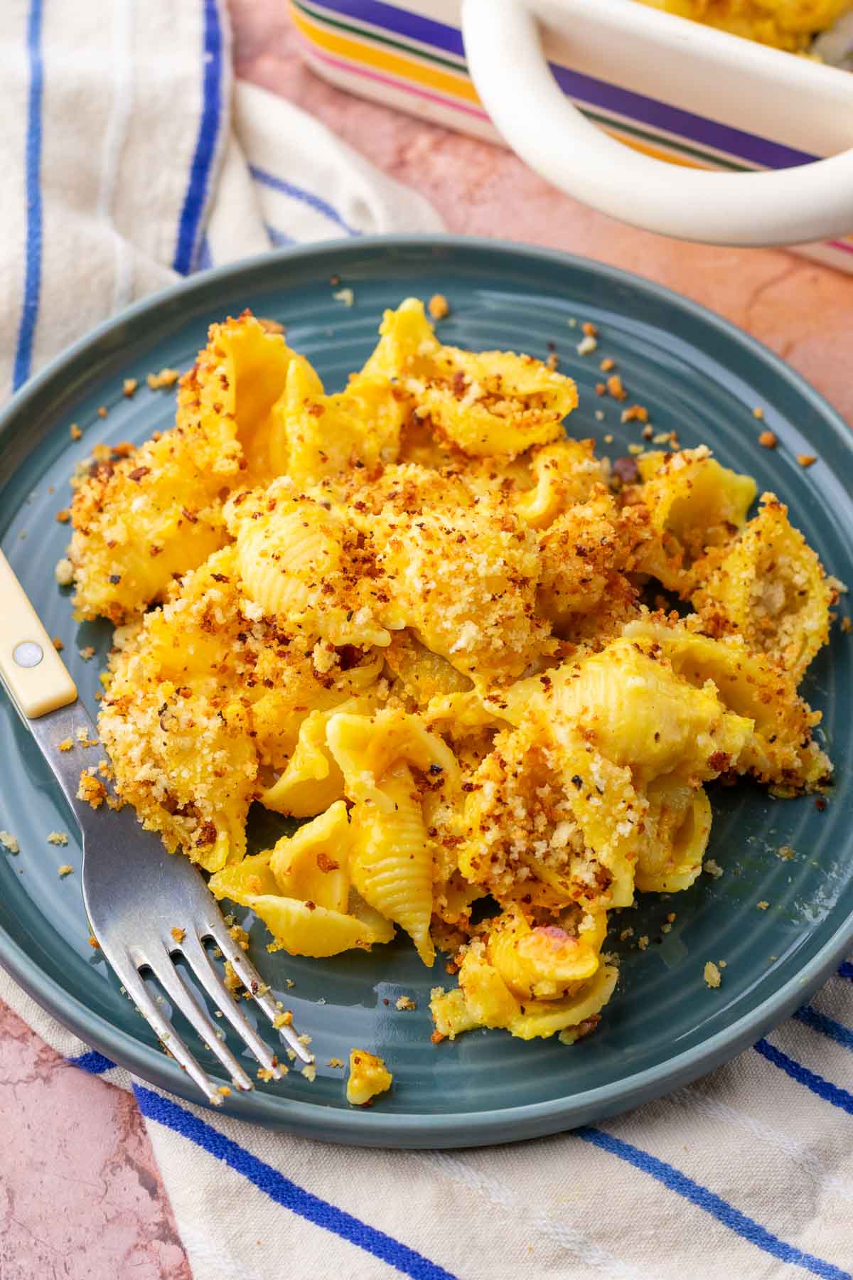 Plate of sourdough mac and cheese with sourdough breadcrumbs with a fork on a towel.