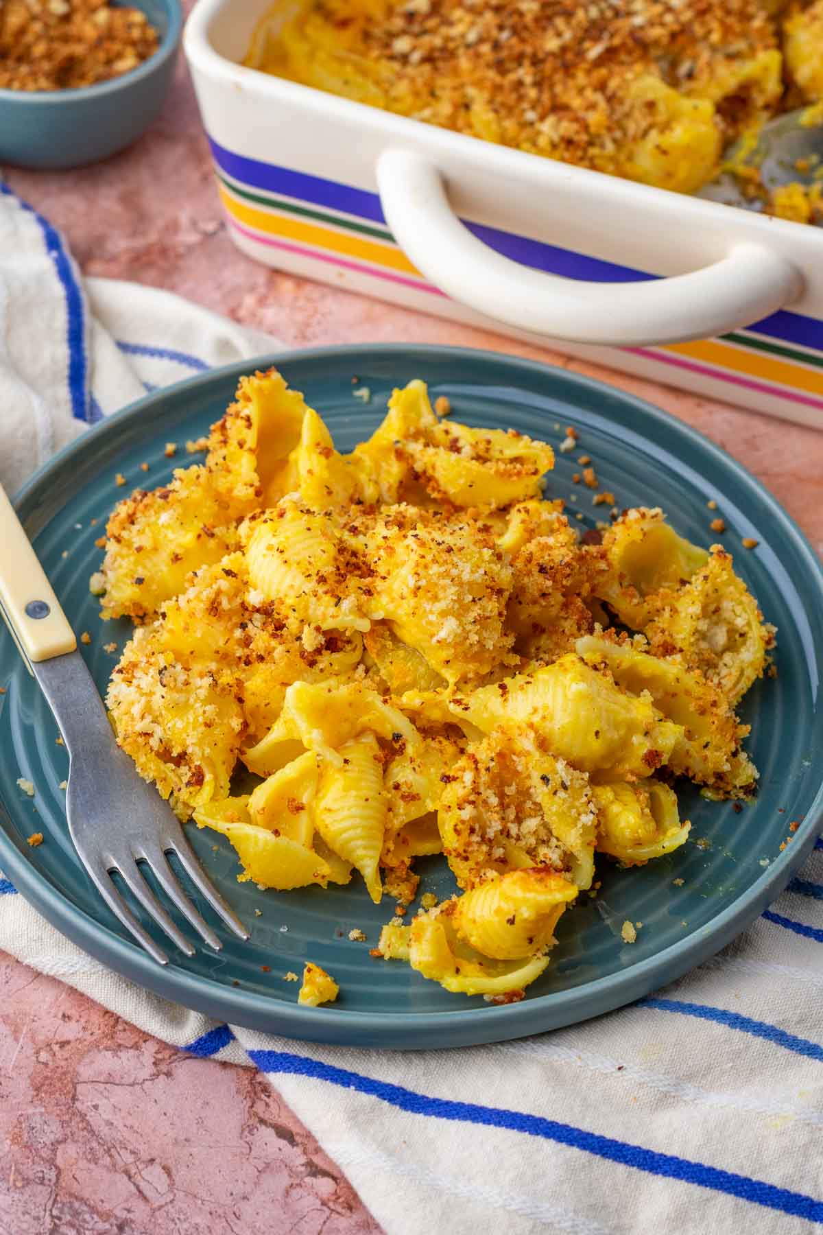 Plate of sourdough mac and cheese with a fork on a striped towel.