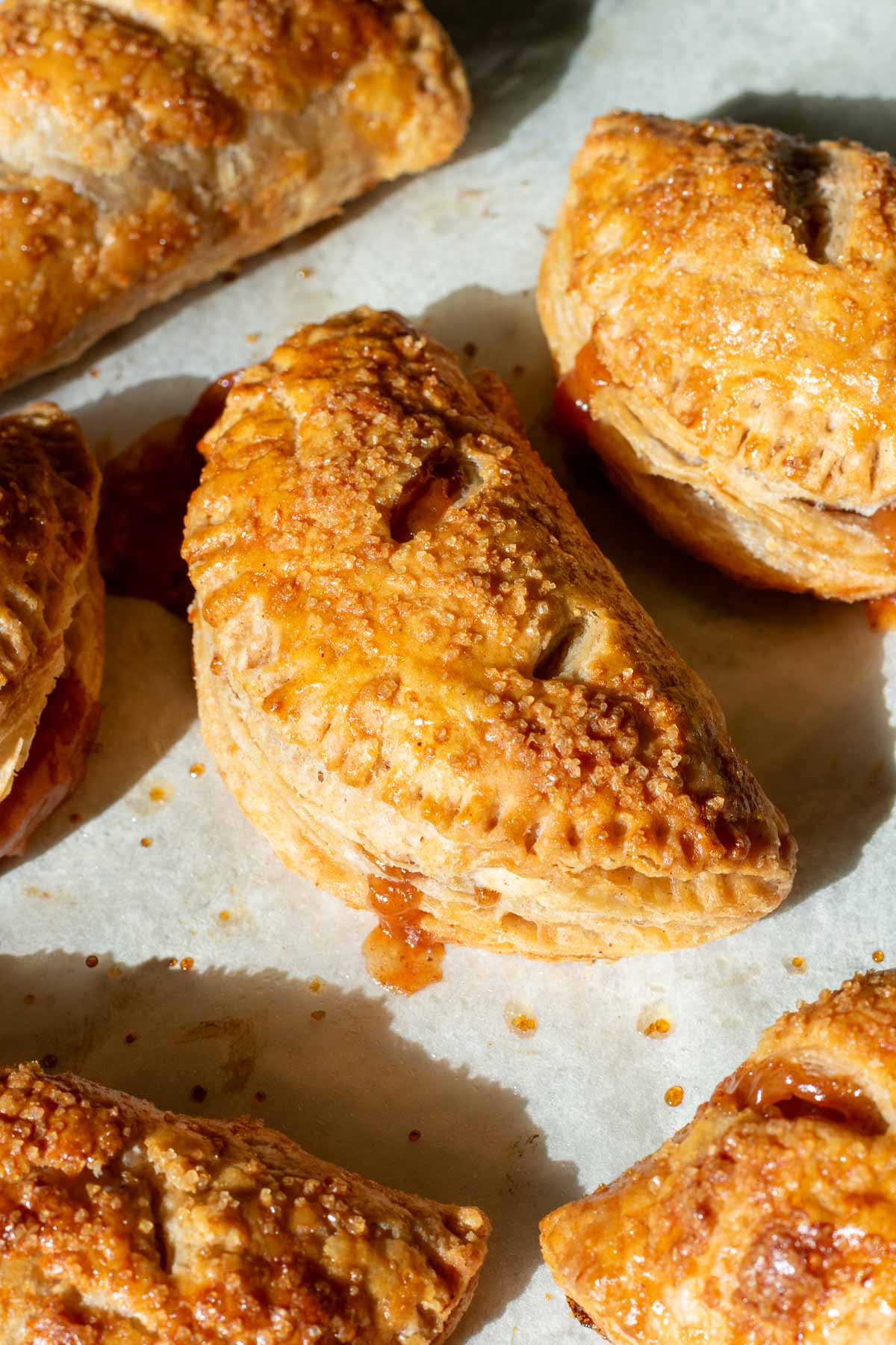 Baked flaky sourdough apple hand pies on parchment paper.