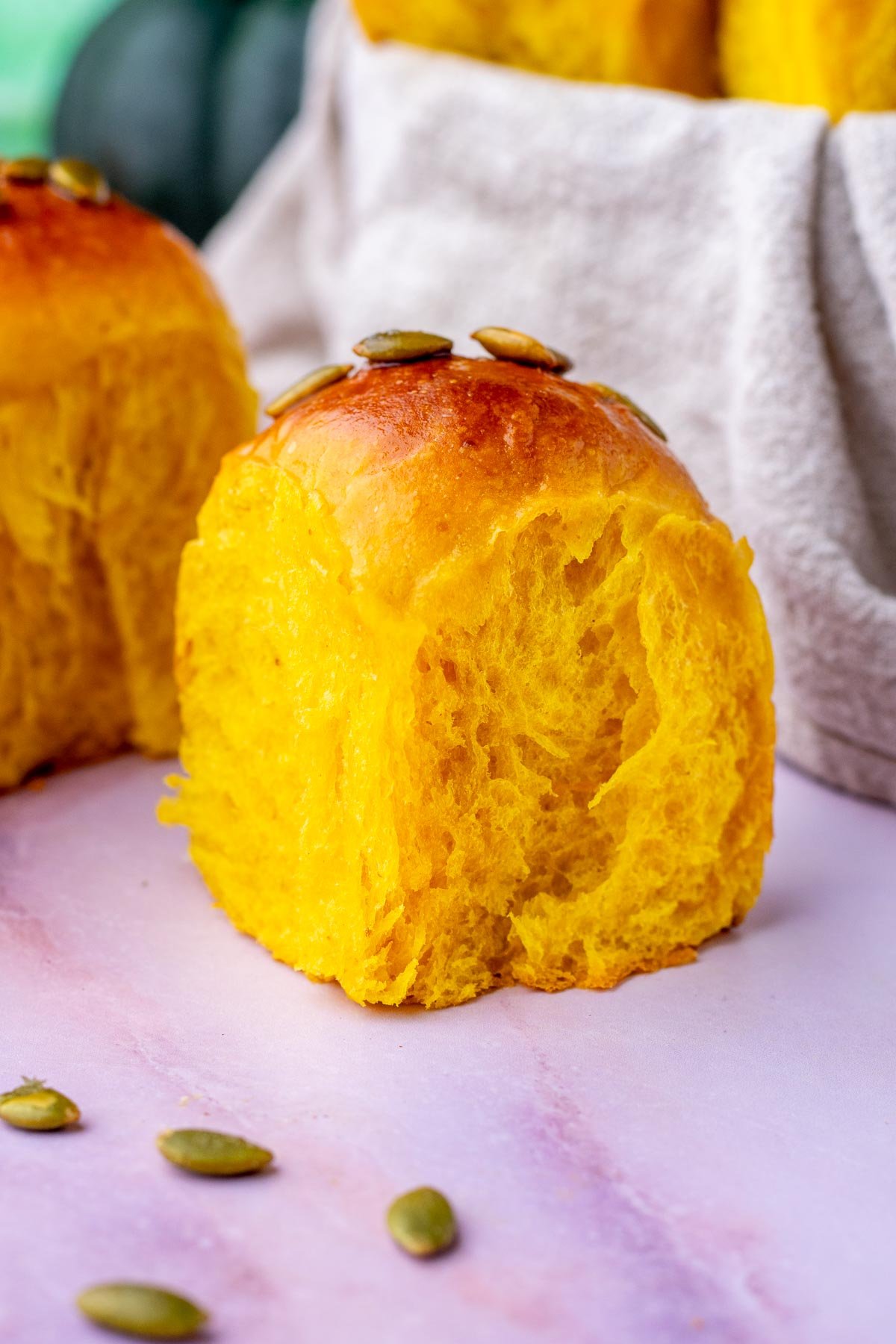 Sourdough pumpkin dinner roll with pumpkin seeds around it.