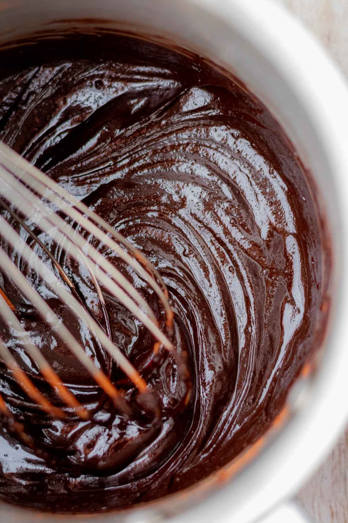 A whisk blooming cocoa powder and butter in a bowl.