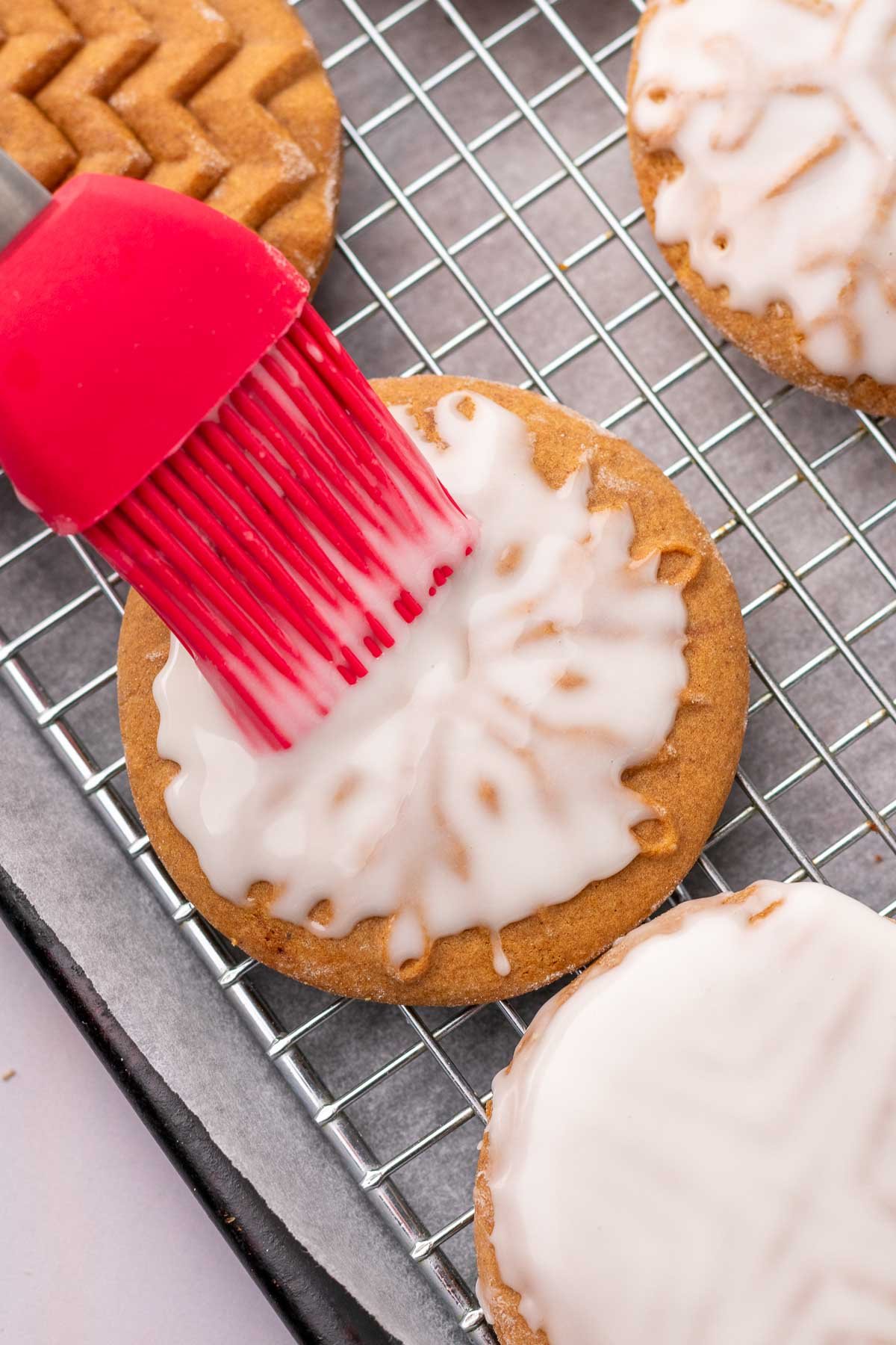 Brushing glaze on a sourdough gingerbread cookie with a pastry brush.