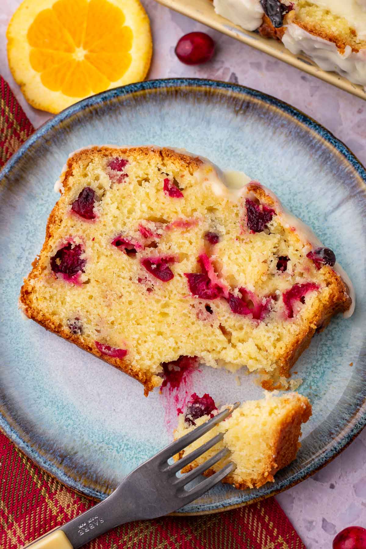 Slice of Cranberry Orange Sourdough Bread on a plate with a fork taking a bite.