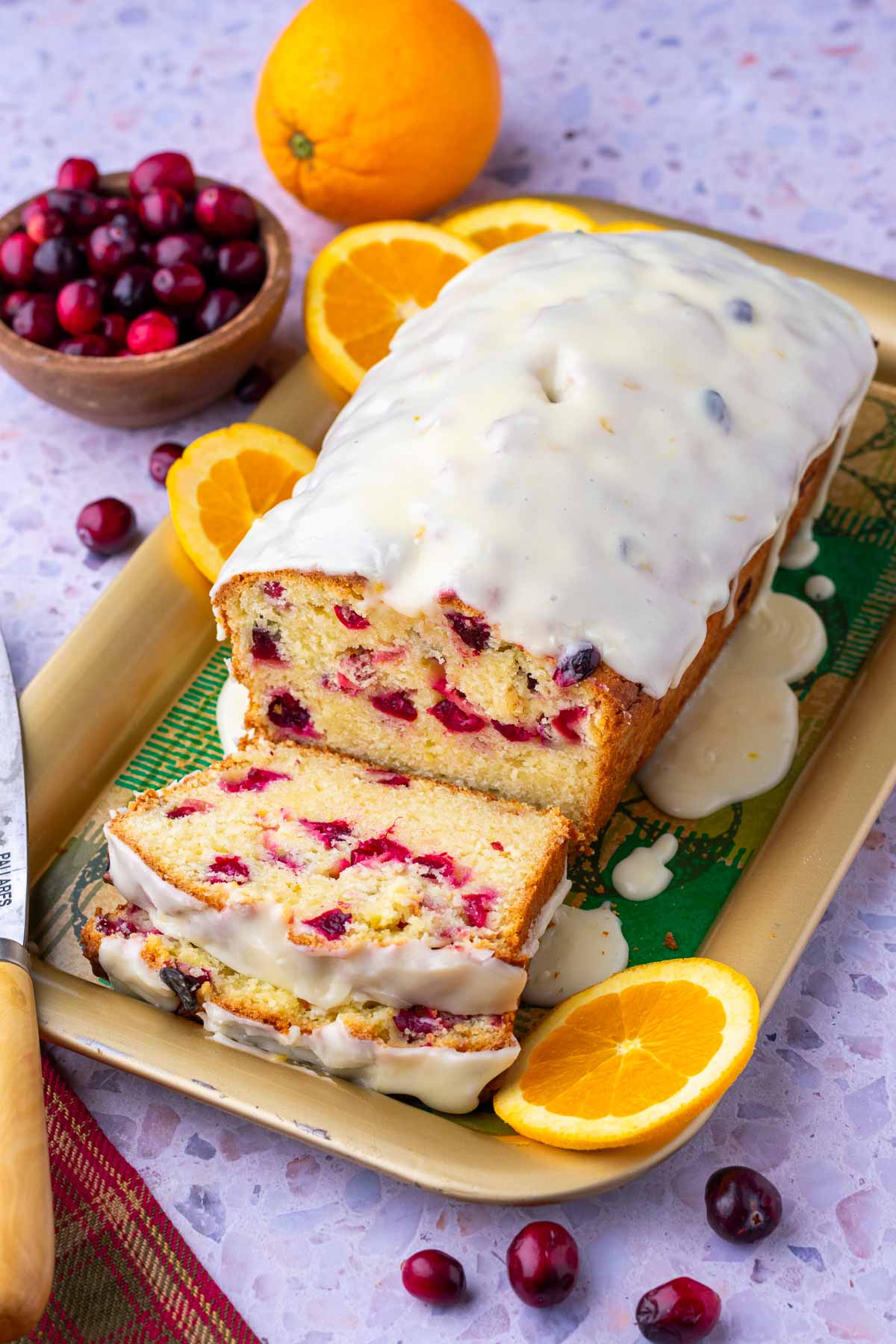 Sliced Cranberry Orange Sourdough Bread on platter surrounded by cranberries and oranges.