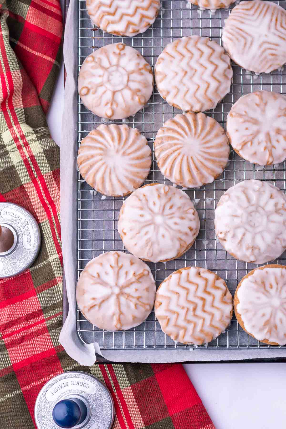 soft glazed sourdough gingerbread cookies on a wire baking rack with a plaid towel.