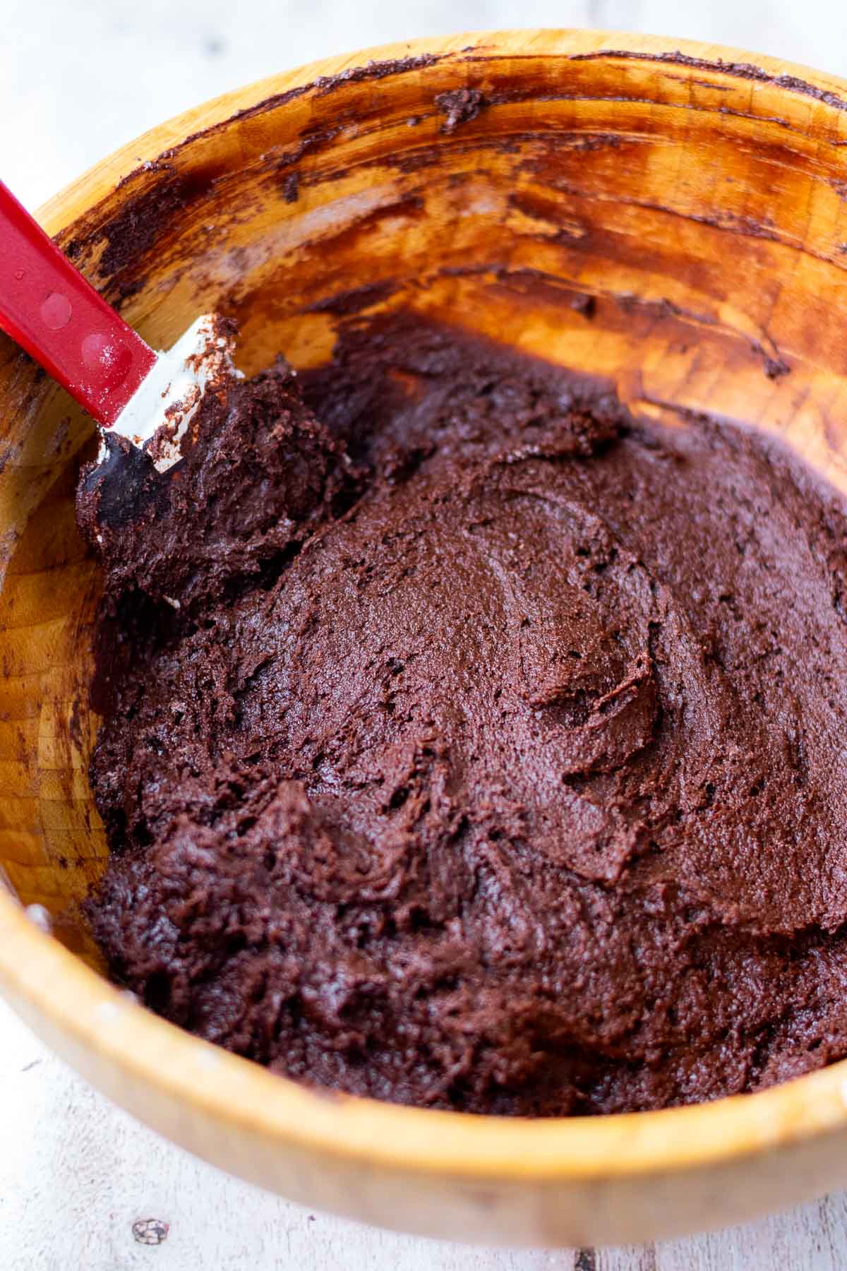 Large wooden bowl with sourdough chocolate crinkle cookie dough and a spatula.