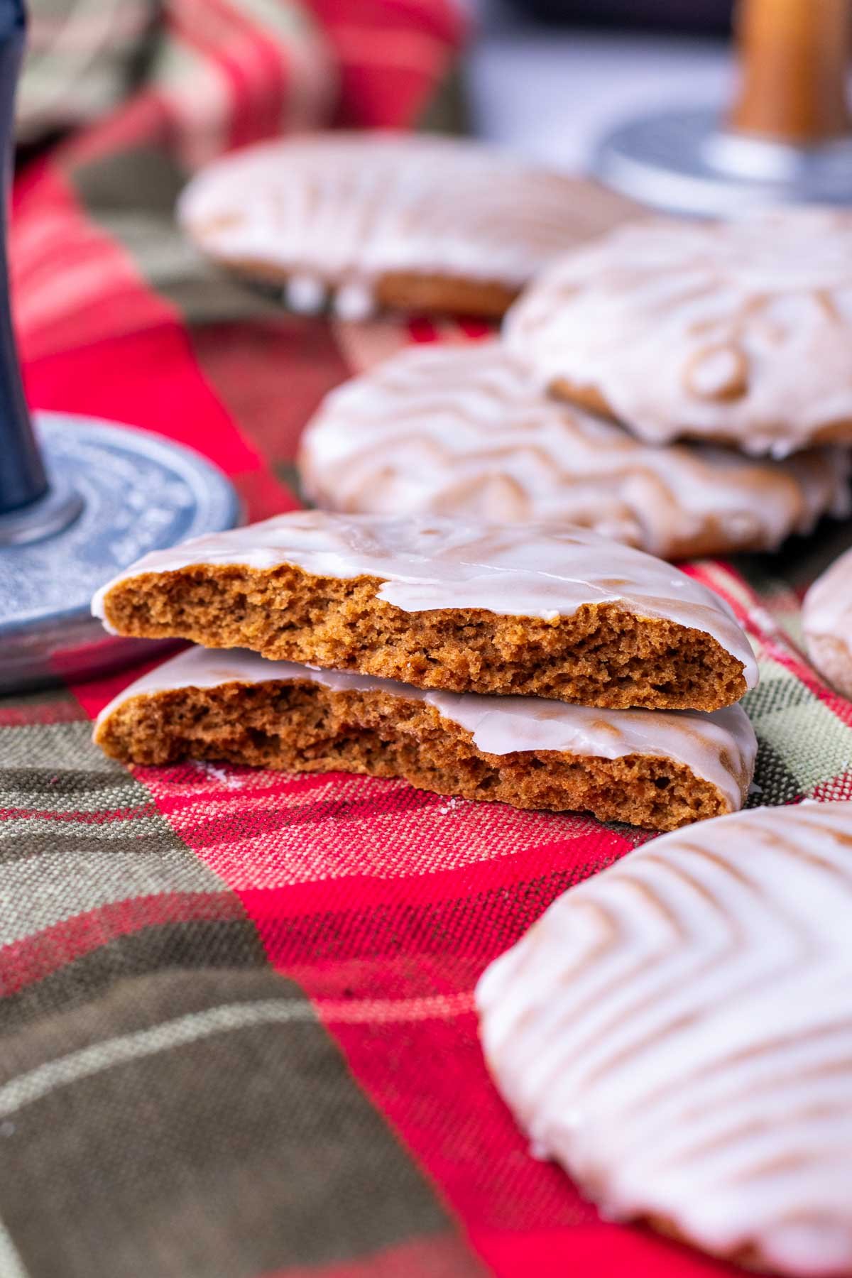 Two broken halves of a soft glazed sourdough gingerbread cookies on a plaid towel with cookies surrounding it.