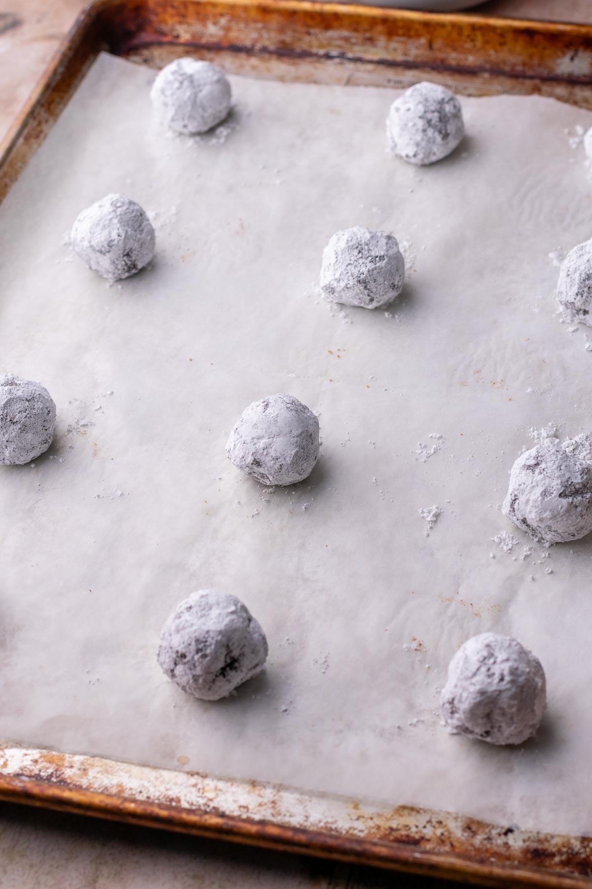 Unbaked sourdough chocolate crinkle cookies on a baking sheet.