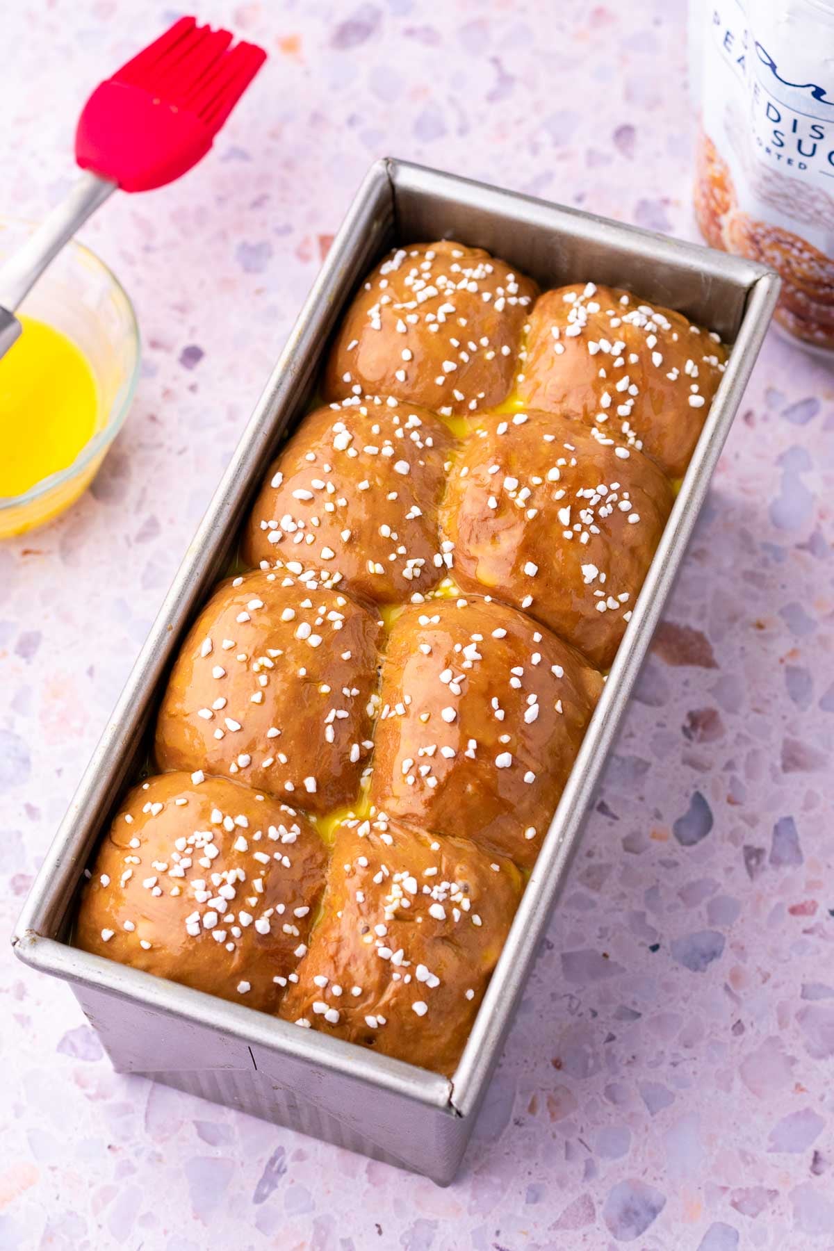 Sourdough chocolate brioche bread at the end of final proofing in a bread loaf pan with an egg wash and swedish pearl sugar on top.