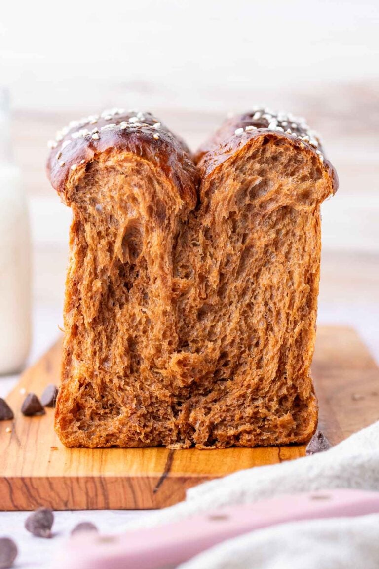 Fluffy sourdough chocolate brioche sliced on a cutting board with chocolate chips.