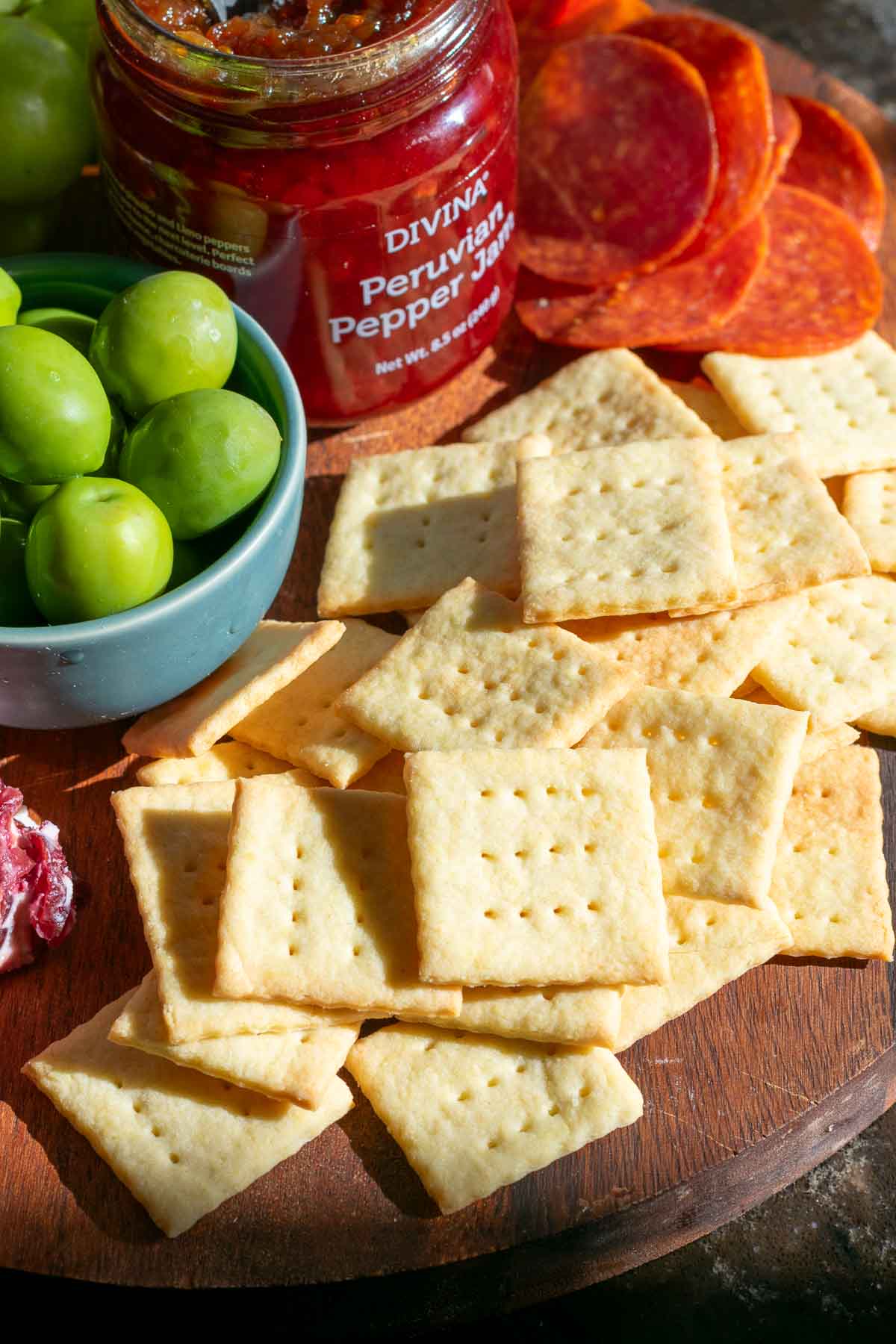 Sourdough Butter Crackers on a cheese board with olives and jam.