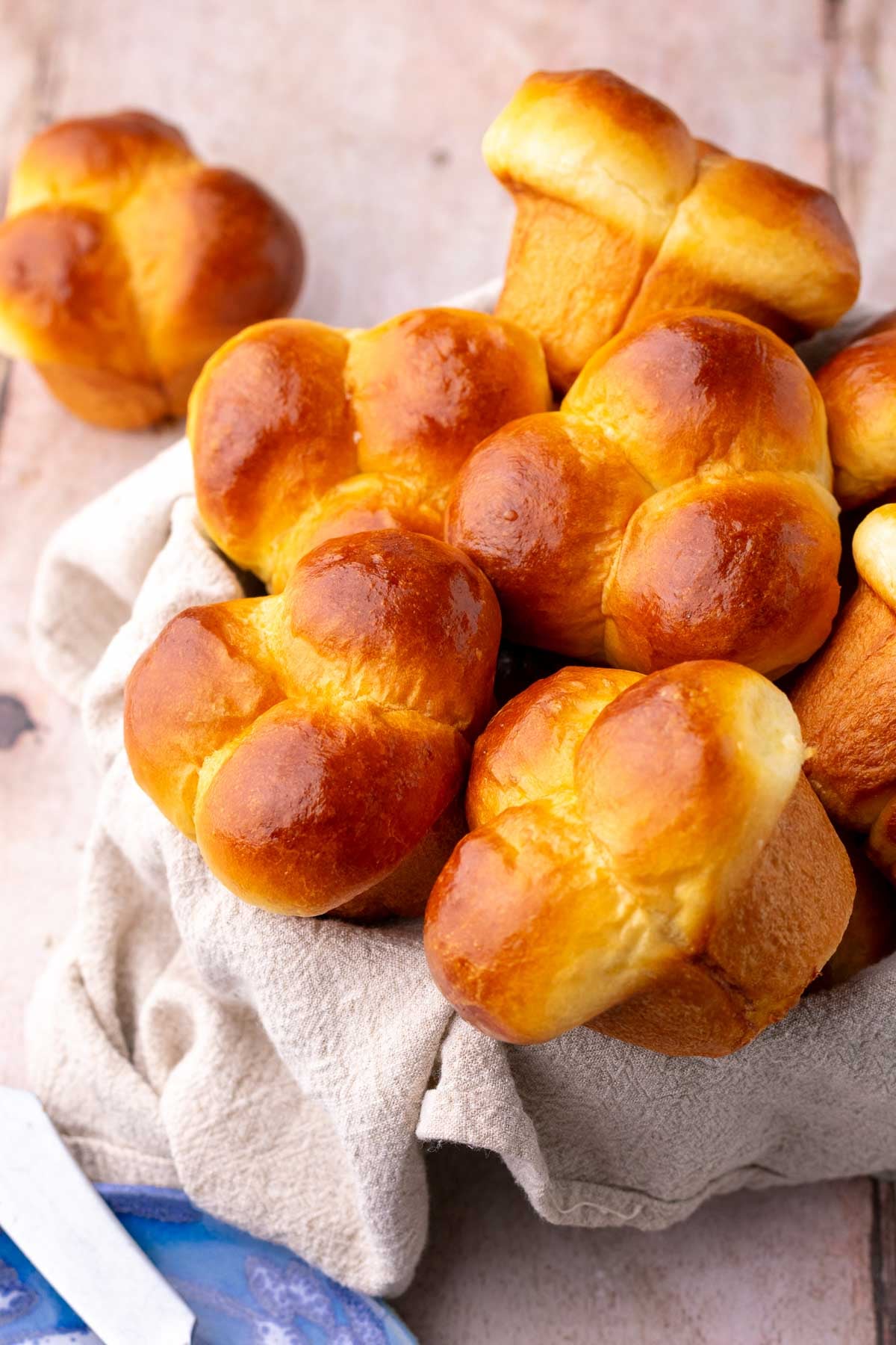 Bowl of cloverleaf sourdough dinner rolls with a towel.