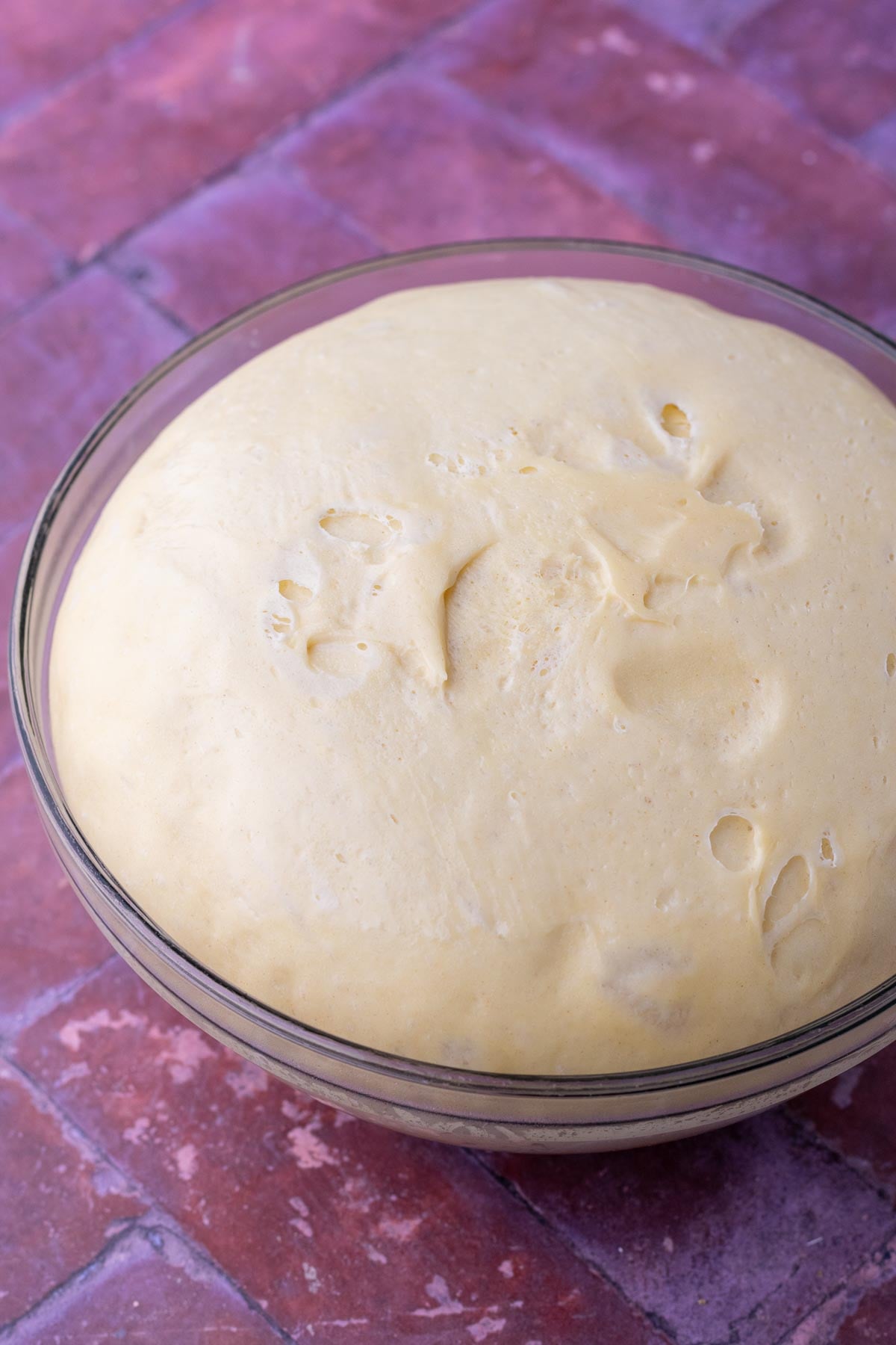 End of bulk fermentation for sourdough brioche dough in a glass bowl.