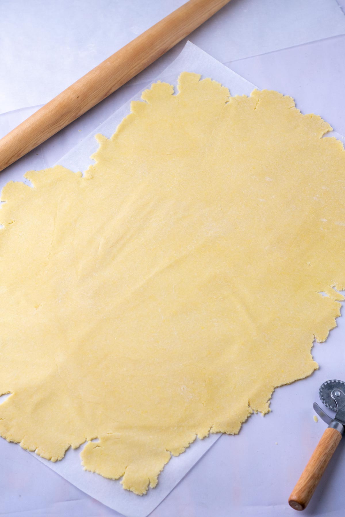 Rolled out Sourdough Butter Crackers on parchment paper with a rolling pin.