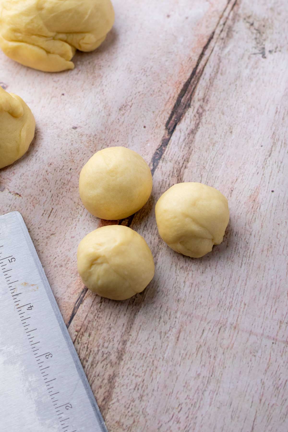 Shaping cloverleaf sourdough dinner rolls into three balls.