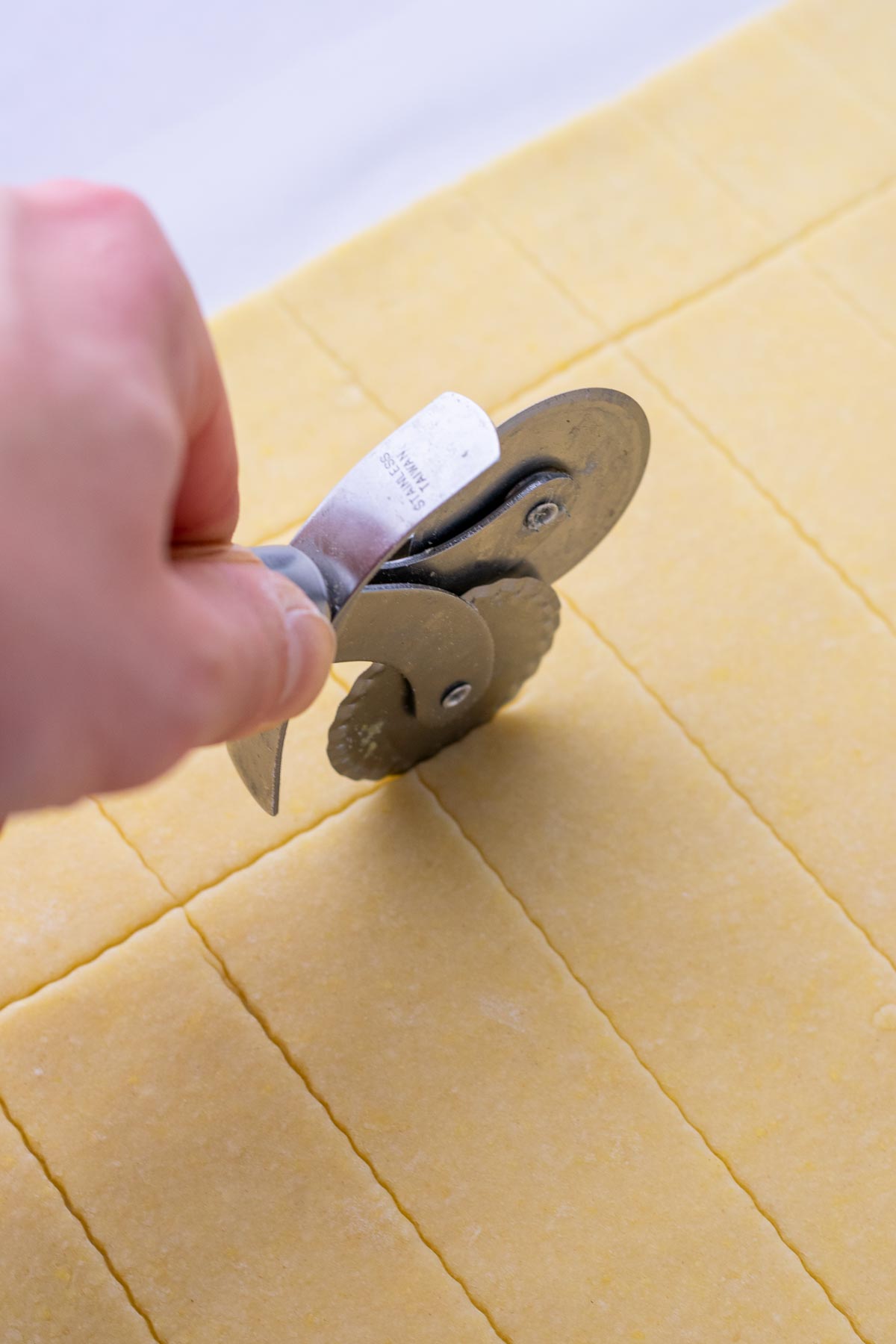 Cutting out Sourdough Butter Crackers with a pastry wheel.
