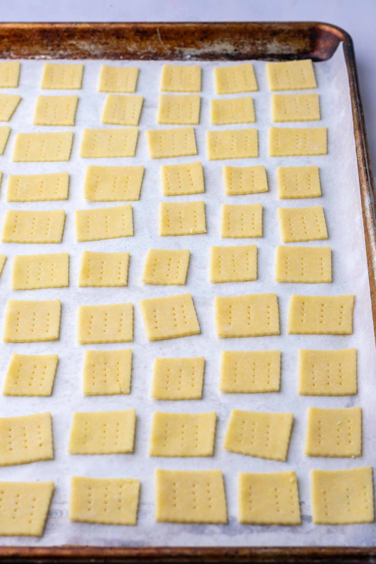 Unbaked Sourdough Butter Crackers on a sheet pan.