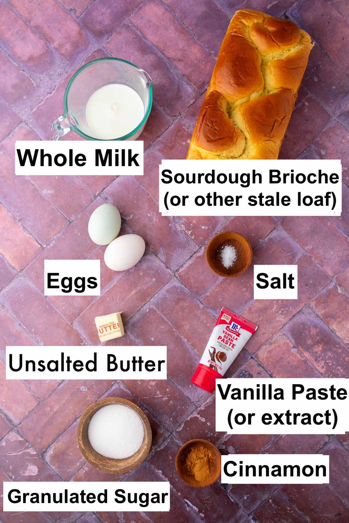 Labeled ingredients needed for sourdough cinnamon french toast sticks including sourdough brioche, whole milk, eggs, salt, unsalted butter, vanilla, granulated sugar, and cinnamon.