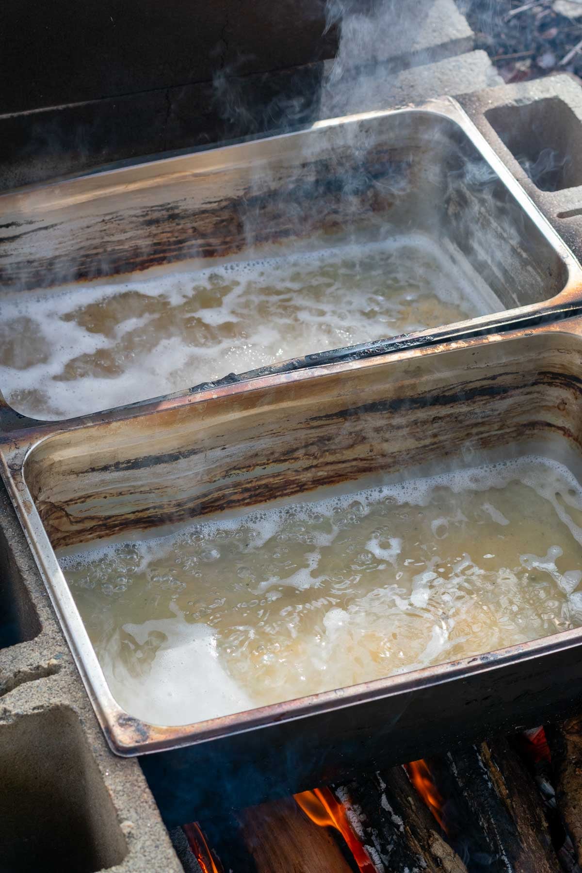 Boiling maple sap outside on a fire in large catering pans.