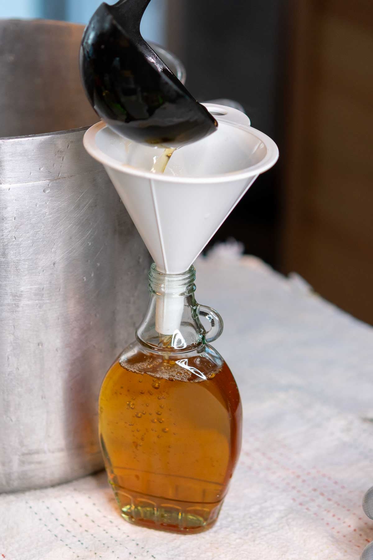 Ladling maple syrup into a jar.