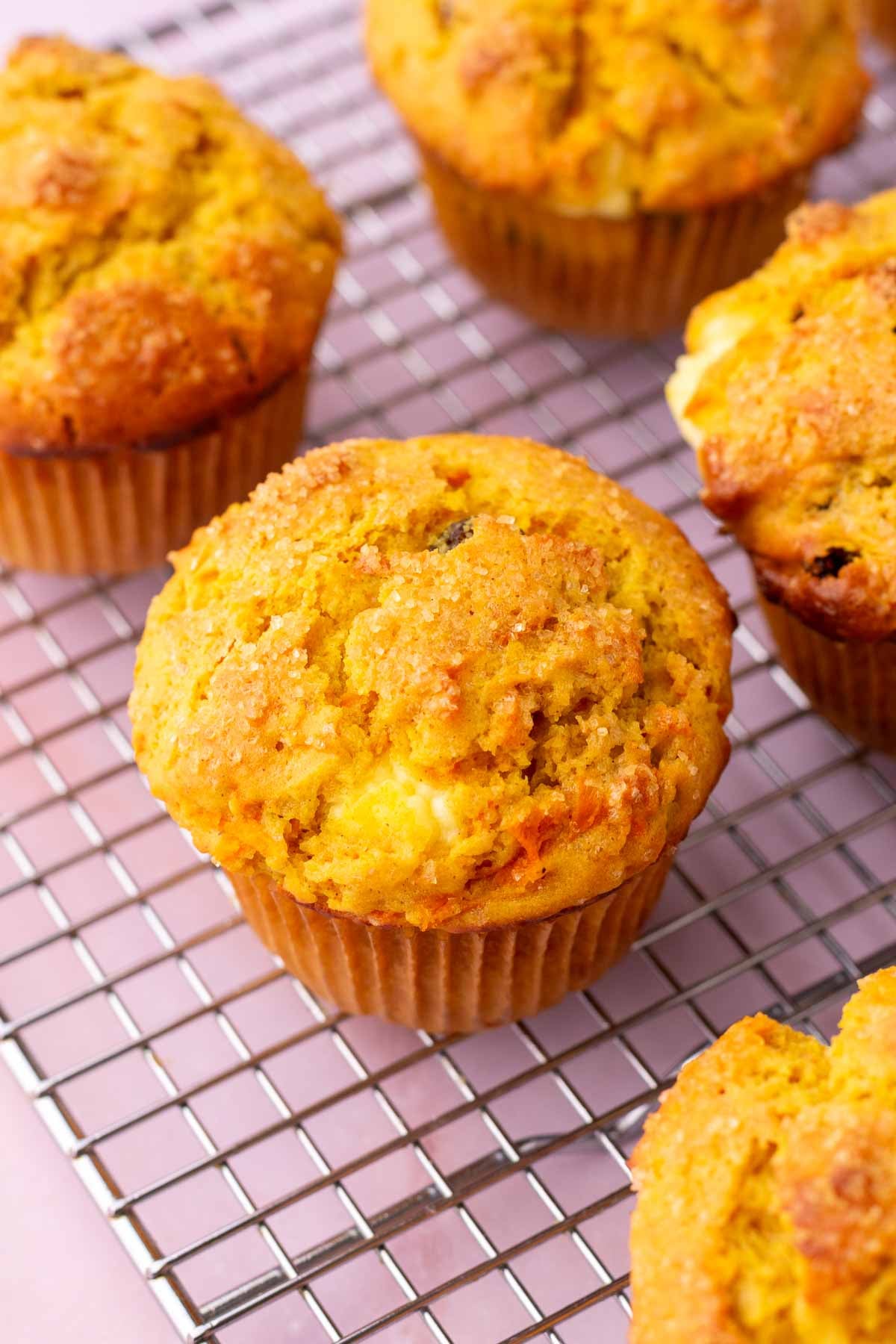 Sourdough carrot cake muffins filled with cream cheese on a wire rack.