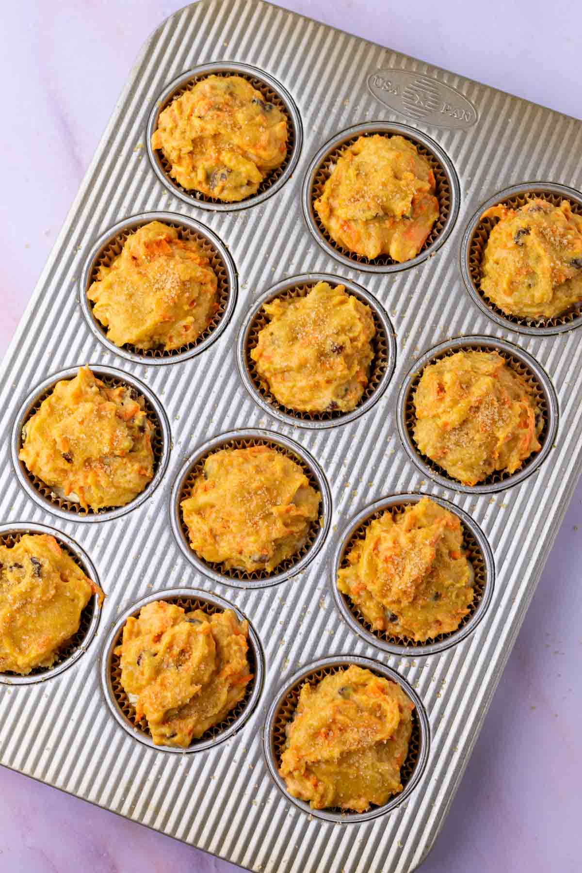 Unbaked sourdough carrot cake muffins in a muffin pan.