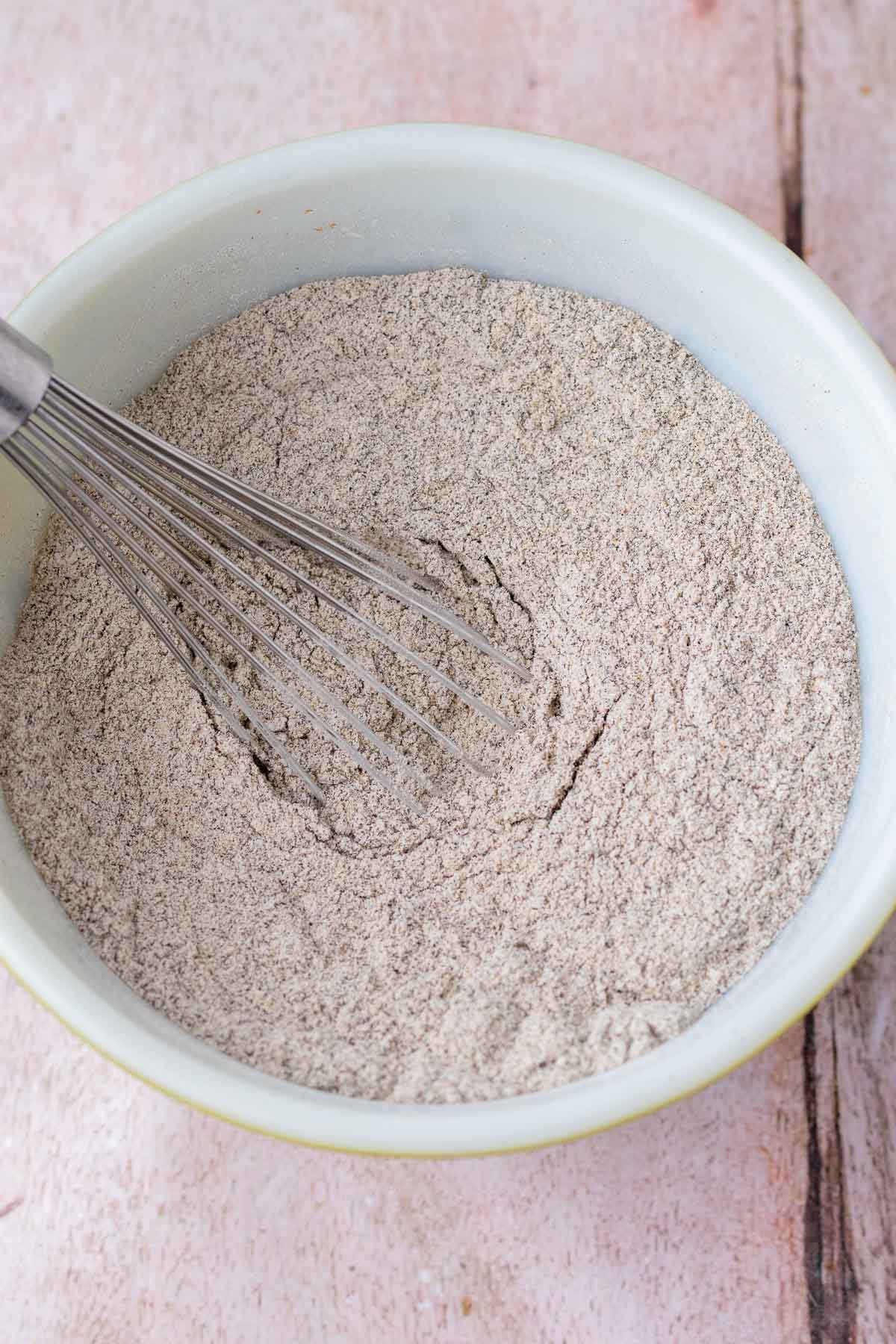 Whisking dry ingredients for sourdough buckwheat chocolate chip cookies in a bowl with a whisk.