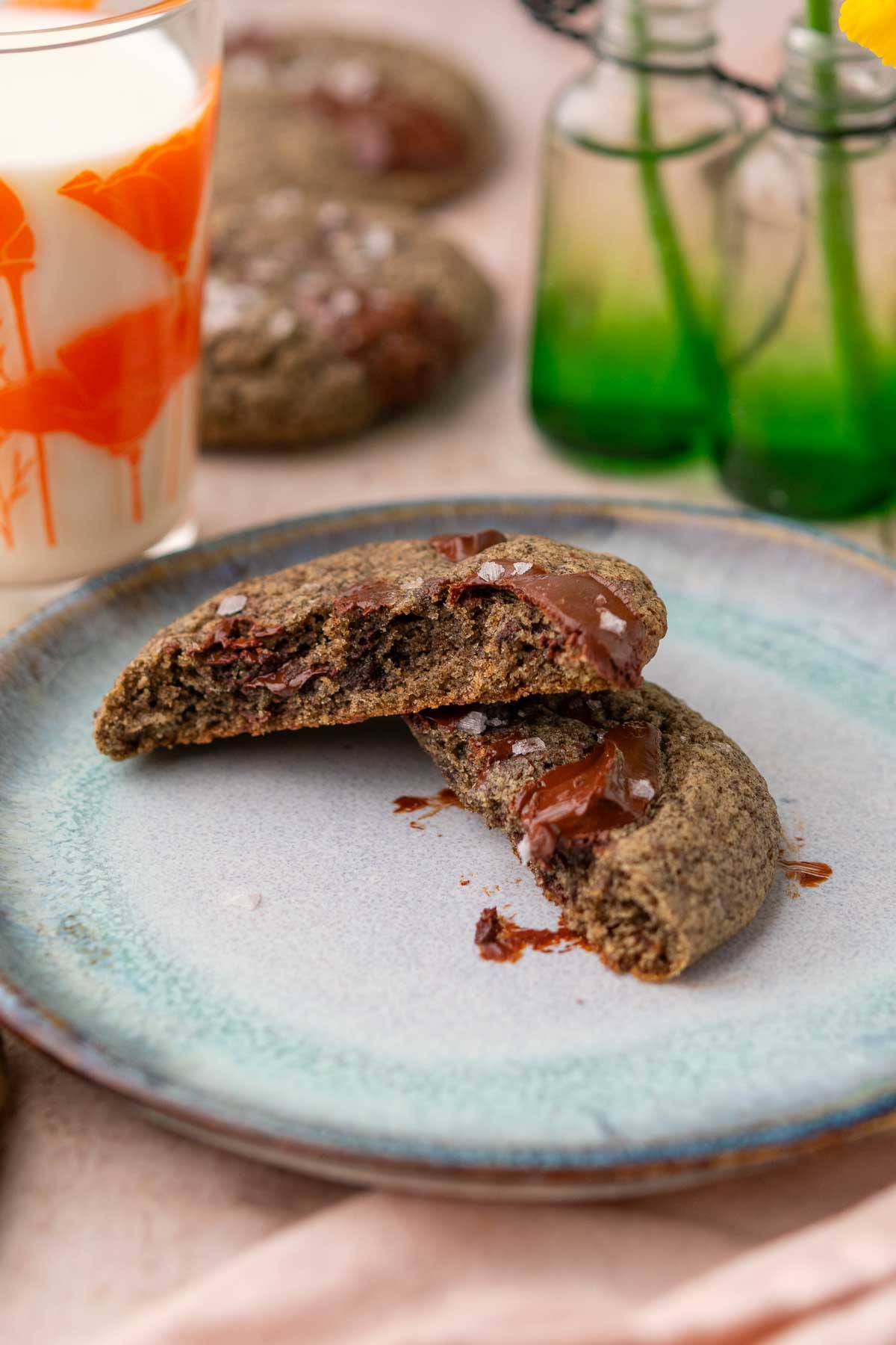 A sourdough buckwheat chocolate chip cookie split in half on a plate.