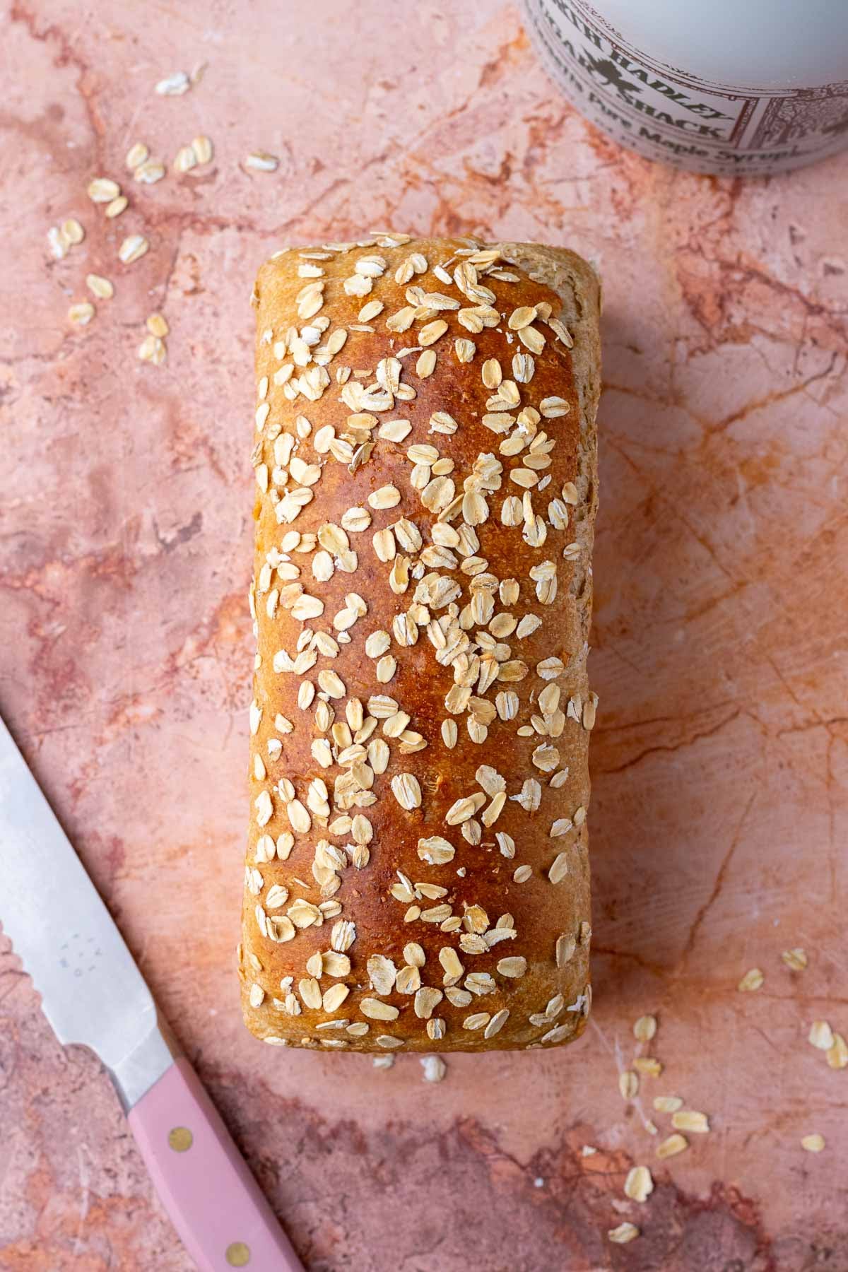 Overhead of a loaf of maple oat sourdough sandwich bread with a bread knife.