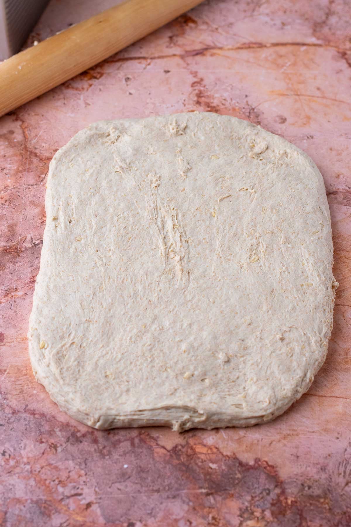 Rolled out maple oat sourdough sandwich bread dough into a rectangular slab.