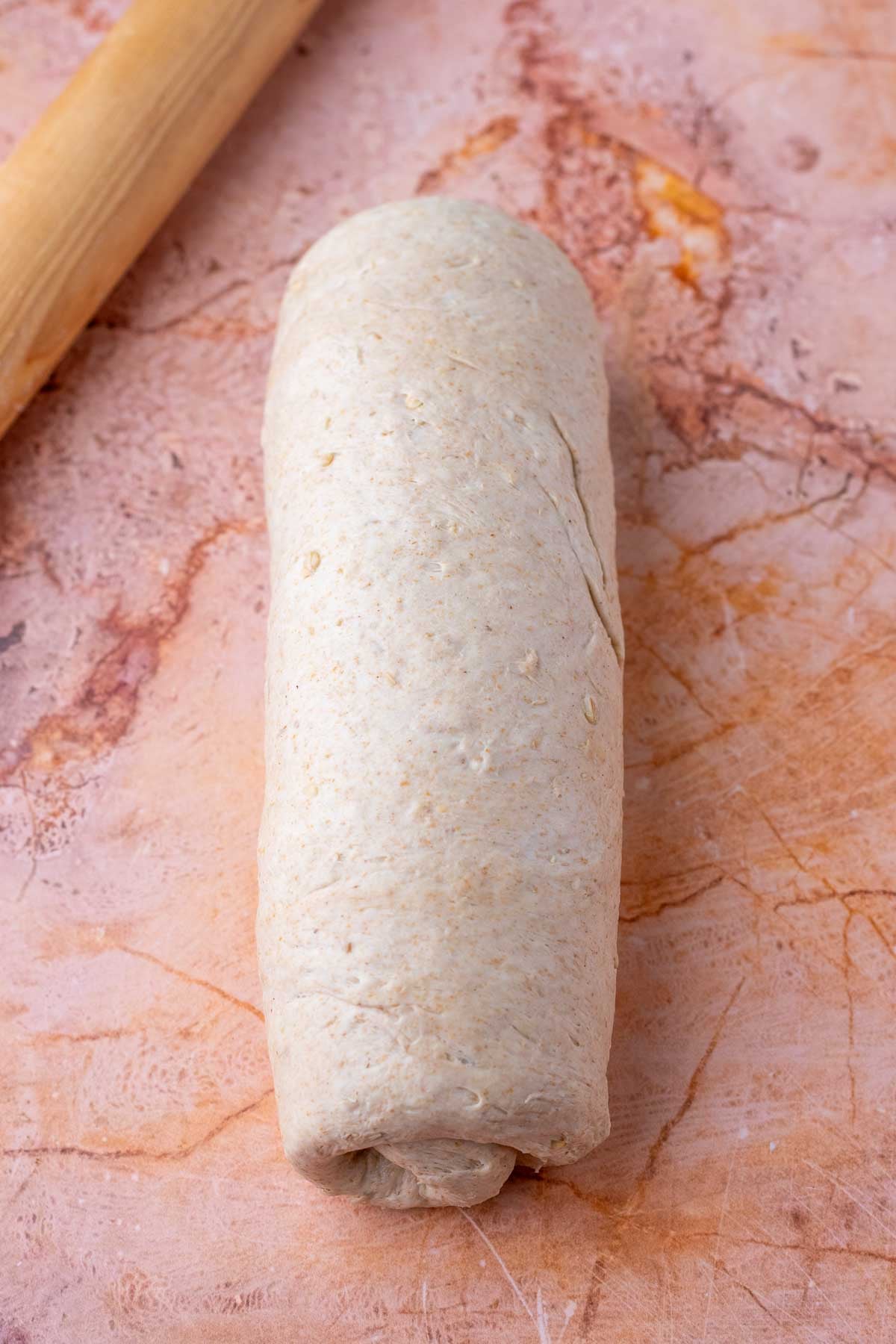Shaped maple oat sourdough sandwich bread into a log.