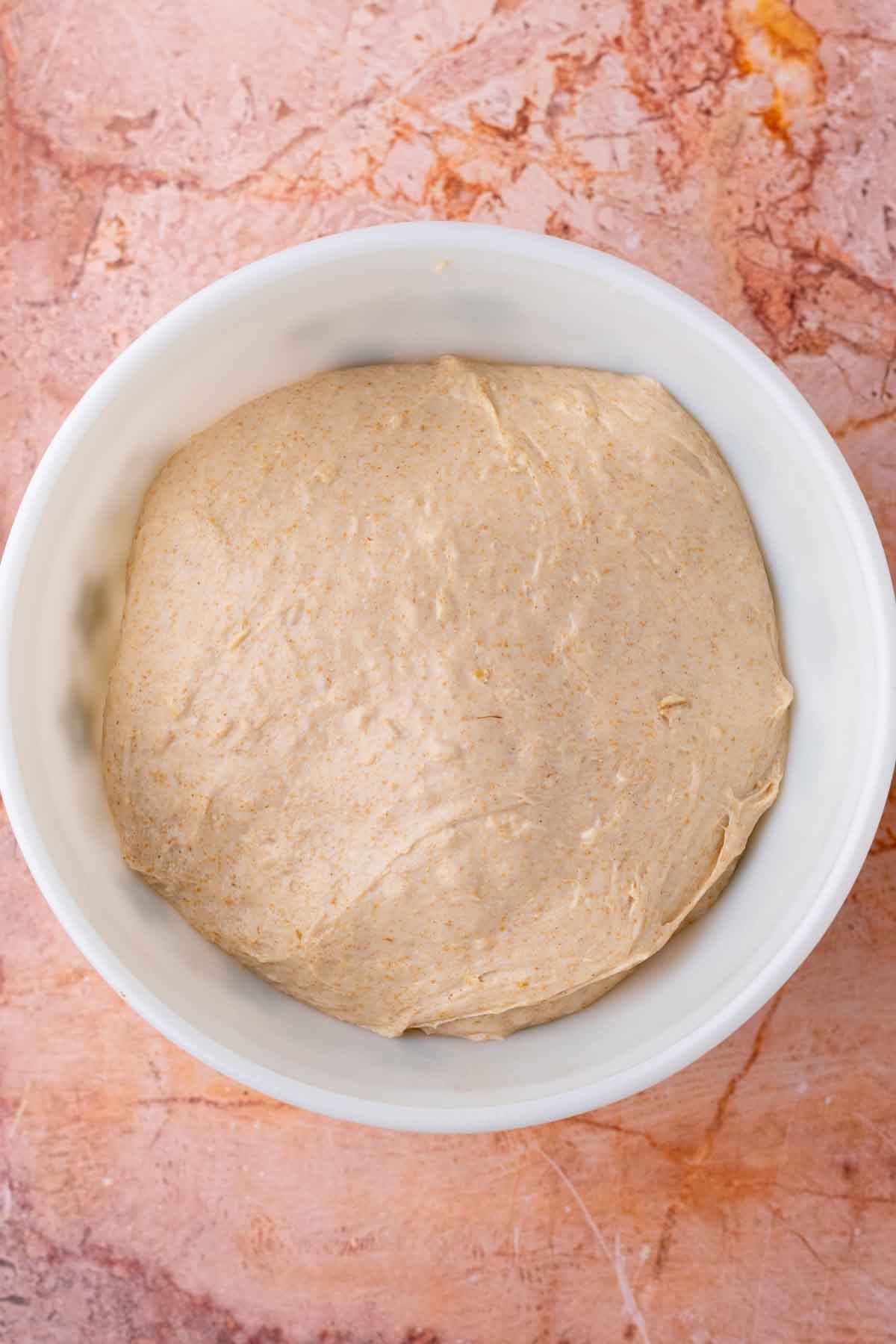 Bowl of maple oat sourdough sandwich bread dough at the start of bulk fermentation.