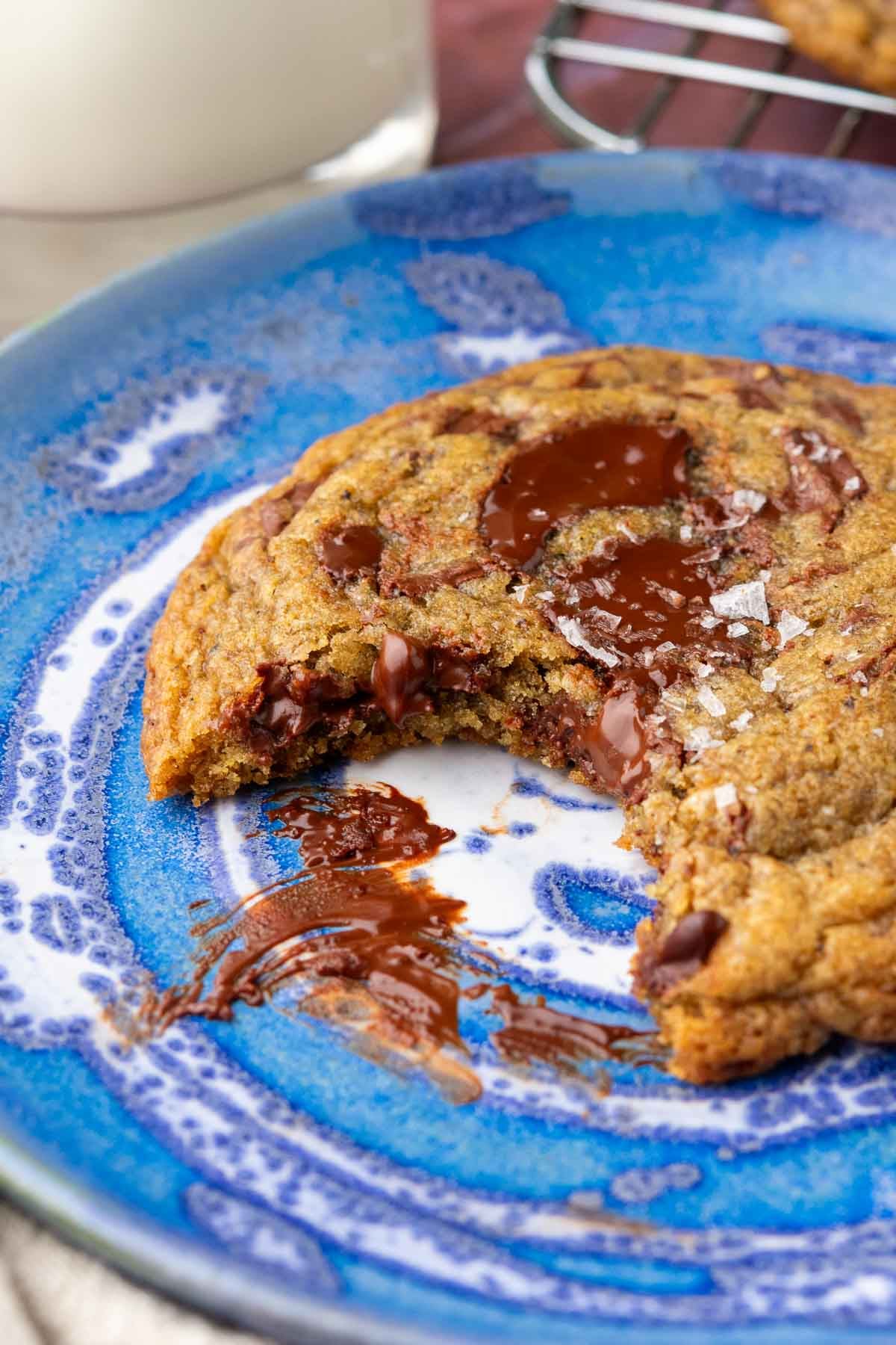 Bite taken out of a sourdough rye chocolate chip cookie on a plate with gooey chocolate.