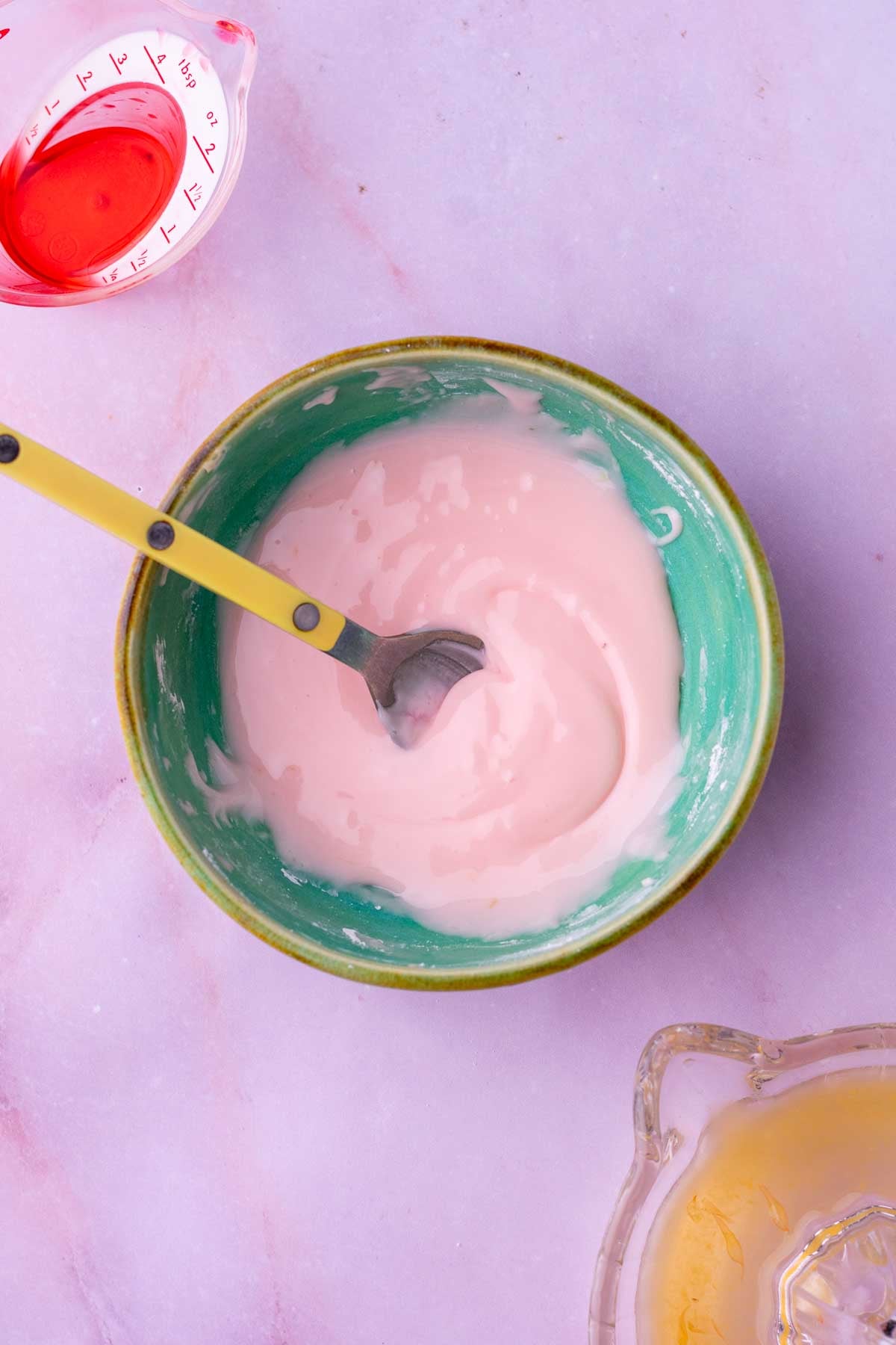 Bowl and spoon with mixed Campari orange glaze for sourdough rhubarb scones.