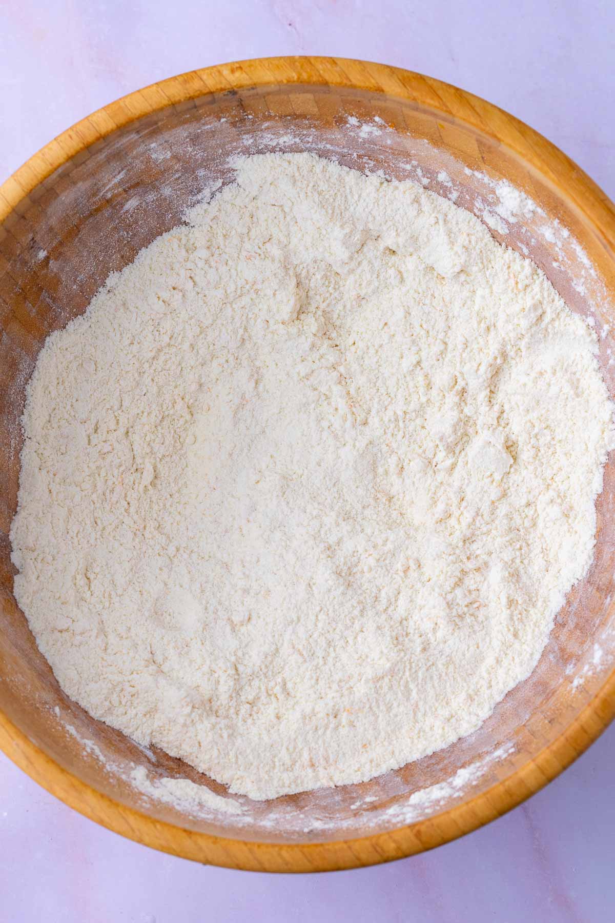 Mixed dry ingredients for sourdough rhubarb scones in a large wooden bowl.