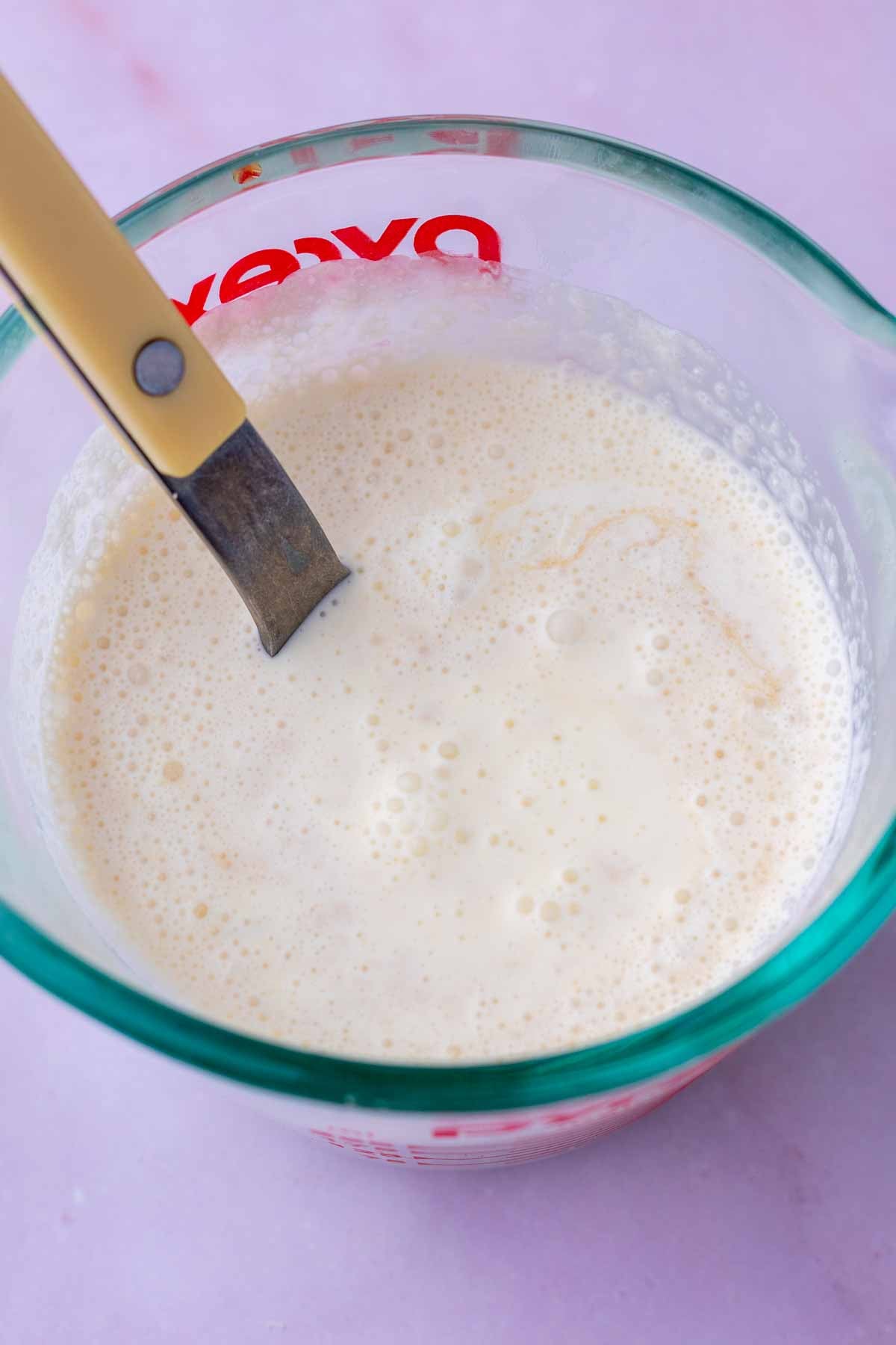 Mixed wet ingredients for sourdough rhubarb scones in a liquid measuring cup and a fork.