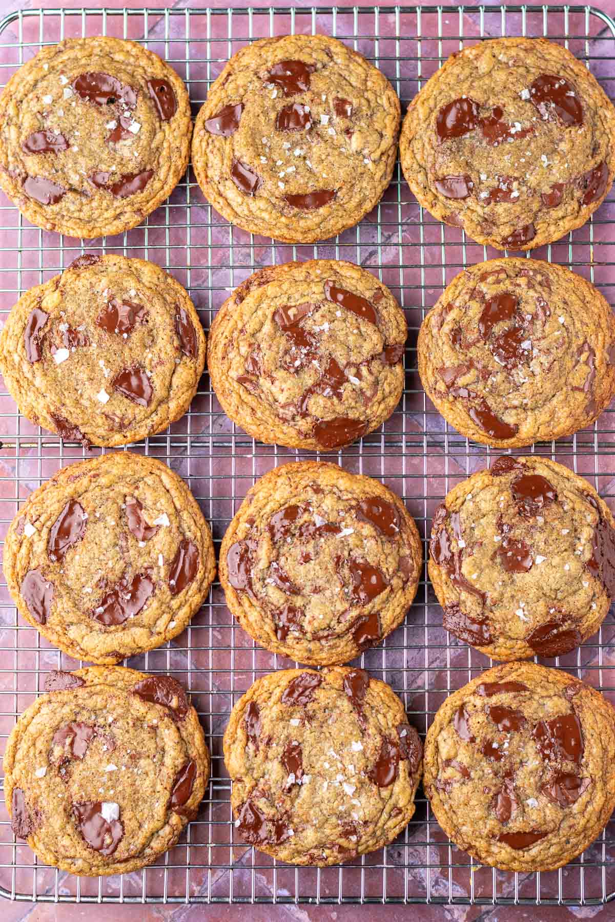 Twelve sourdough rye chocolate chip cookies on a cooling rack.