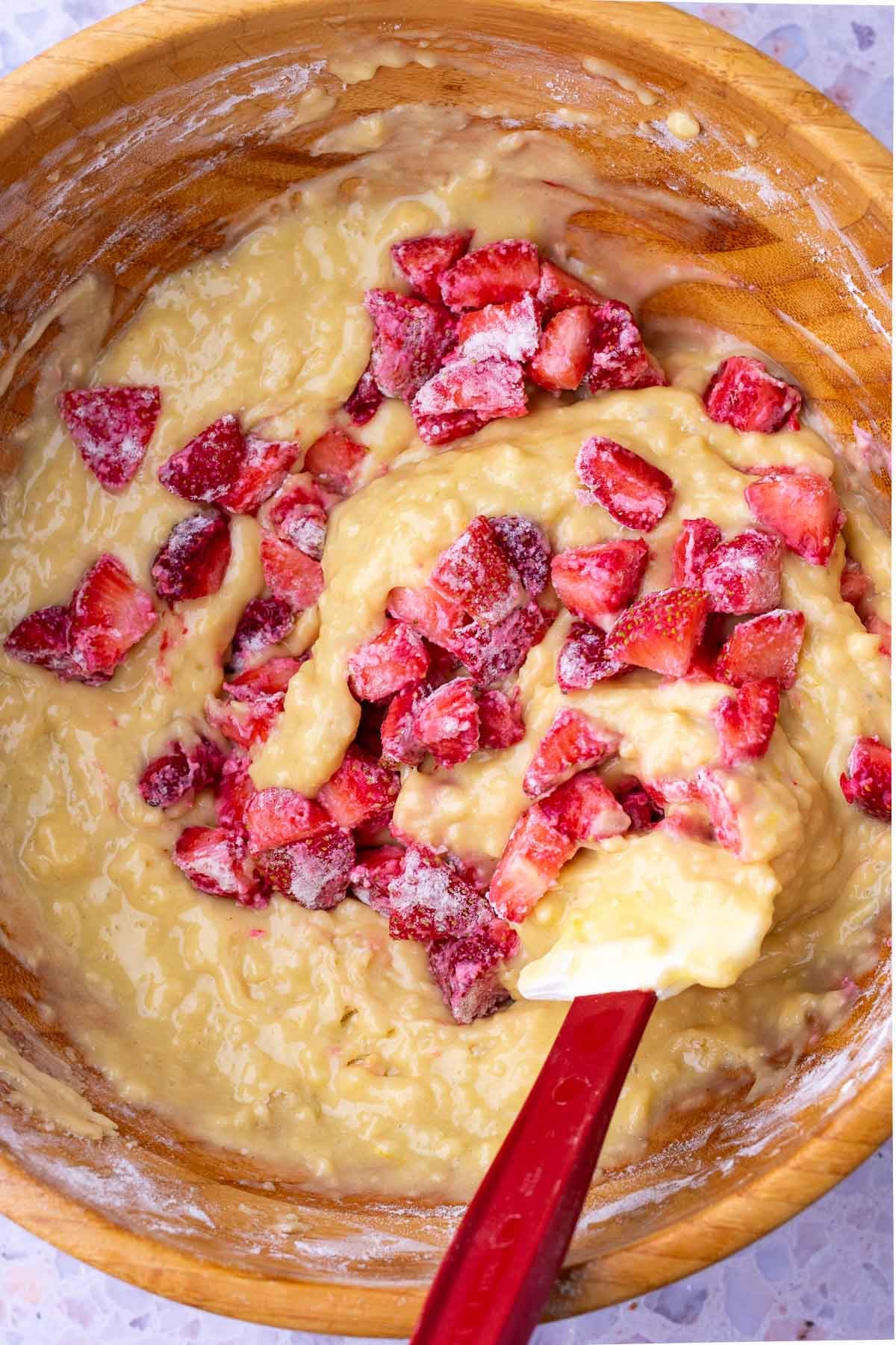 Mixing strawberries into Sourdough Strawberry Bread batter with a spatula.